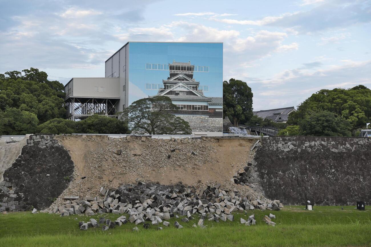 崩落した熊本城の石垣。奥は素屋根で覆われた宇土櫓（うとやぐら）＝29日午後6時40分、熊本市（共同）