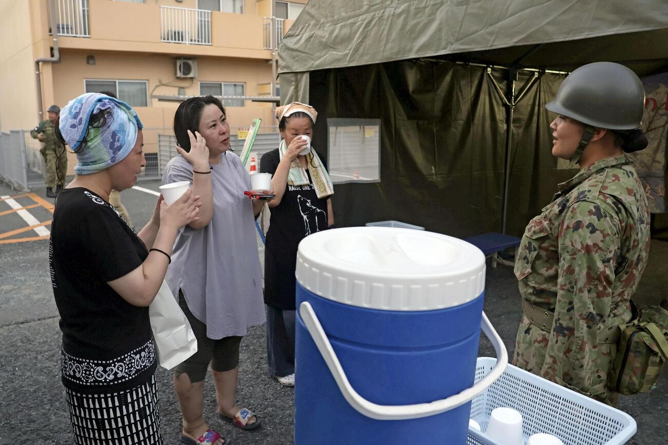 陸上自衛隊が設置した仮設風呂を利用し、隊員と話す被災者（共同）