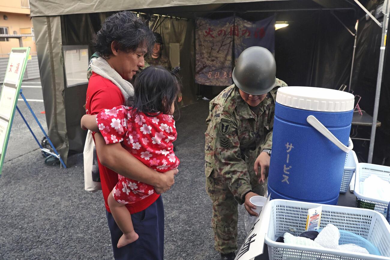 陸上自衛隊が設置した仮設風呂を利用し、隊員から水をもらう被災者（共同）