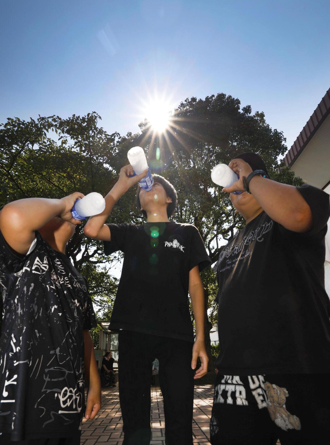 厳しい暑さとなり、水分補給する子どもたち＝3日午前、熊本県八代市（共同）