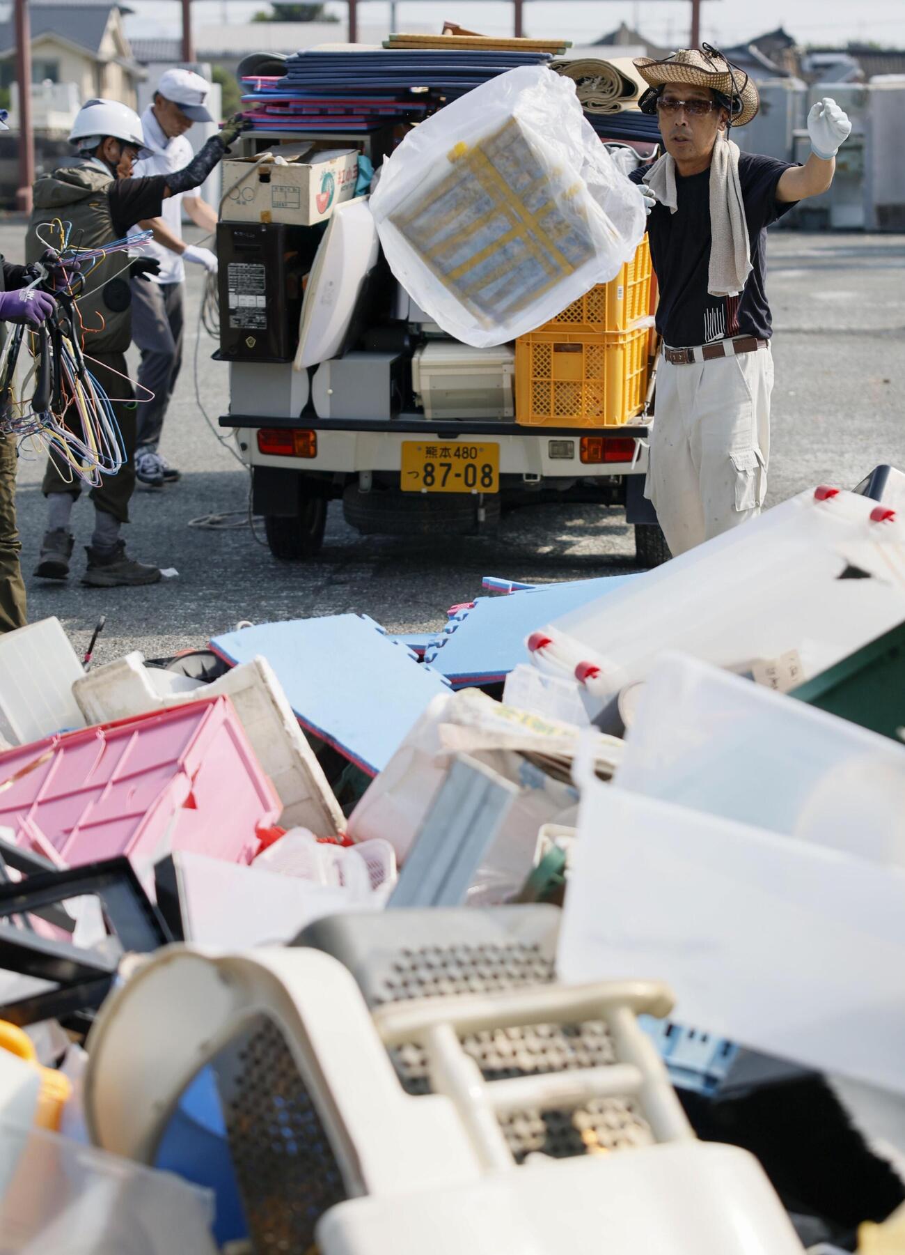 仮置き場に持ち込んだ災害ごみを荷台から降ろす男性（共同）