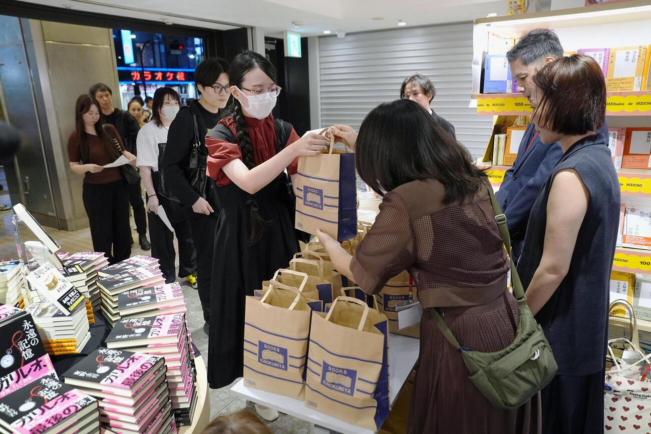 紀伊国屋書店新宿本店で、東野圭吾さんの新刊小説を受け取る人たち＝5日未明、東京都新宿区（共同）