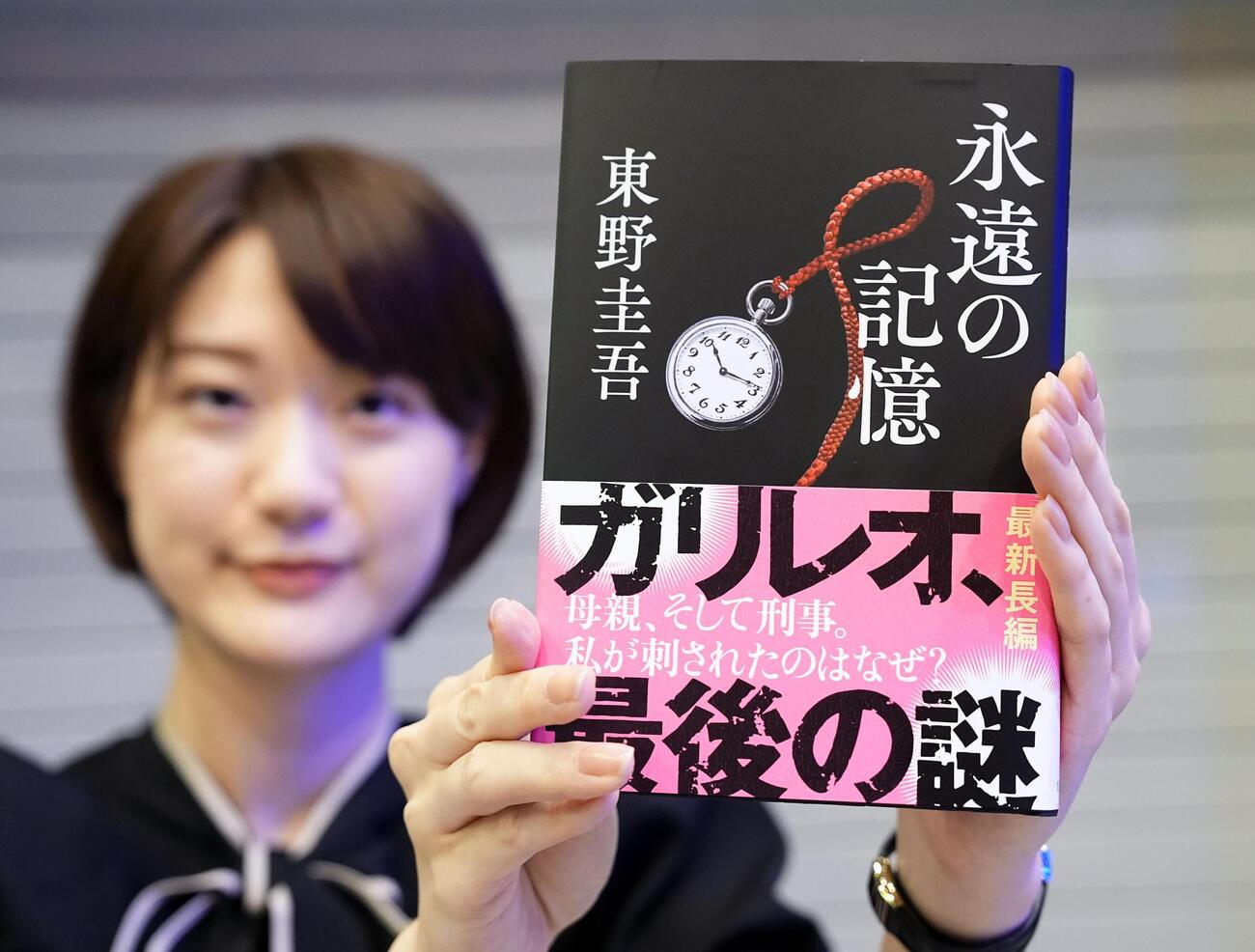 東野圭吾さんの新刊小説「永遠の記憶」を手にする女性＝5日未明、東京都新宿区（共同）