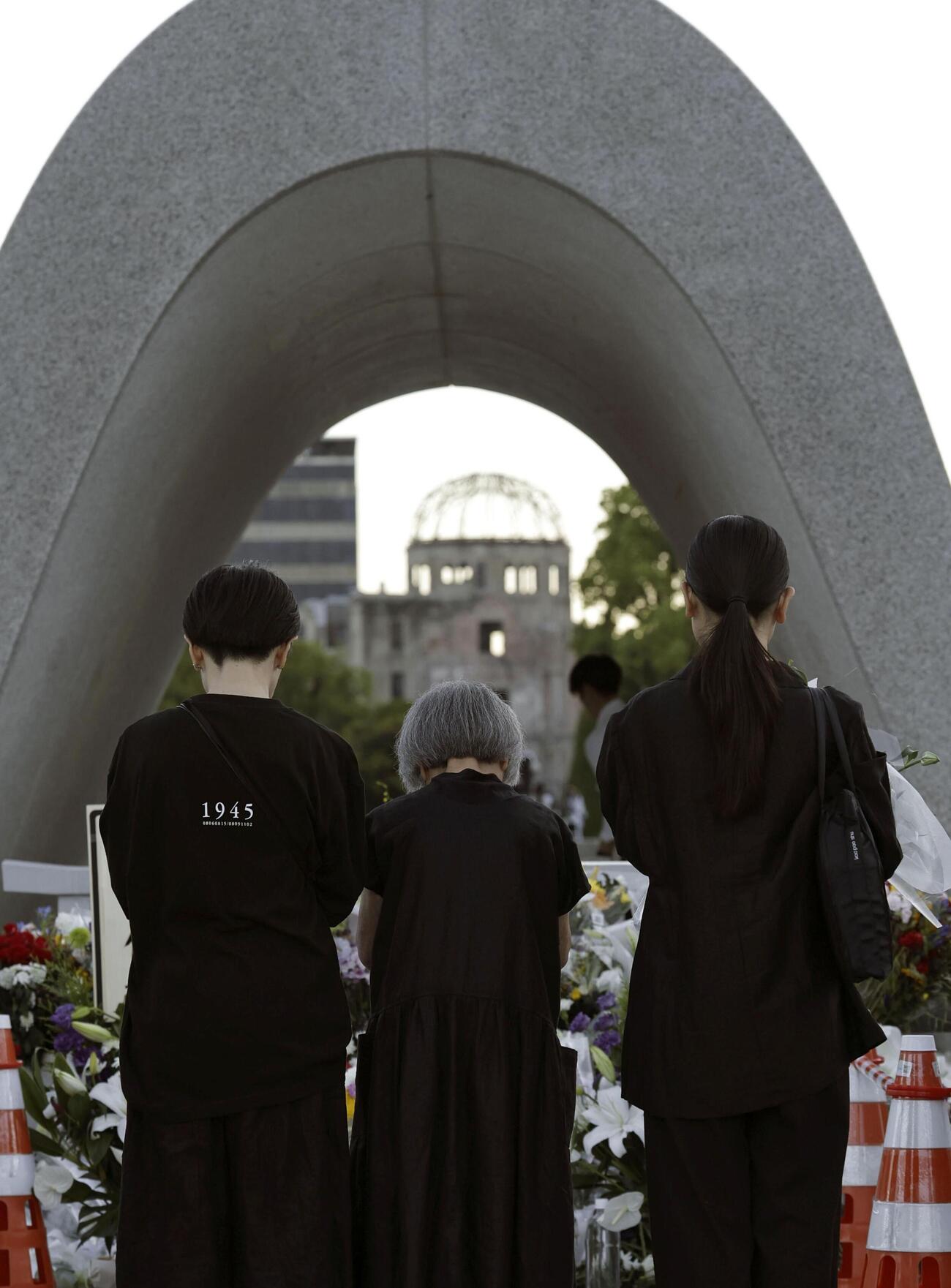 原爆投下から81年の「原爆の日」を迎え、平和記念公園で慰霊碑に手を合わせる人たち（共同）