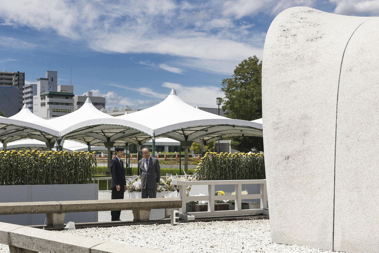 広島市の平和記念公園で原爆慰霊碑に供花し、松井一実市長（右）から説明を受けられる悠仁さま（共同）