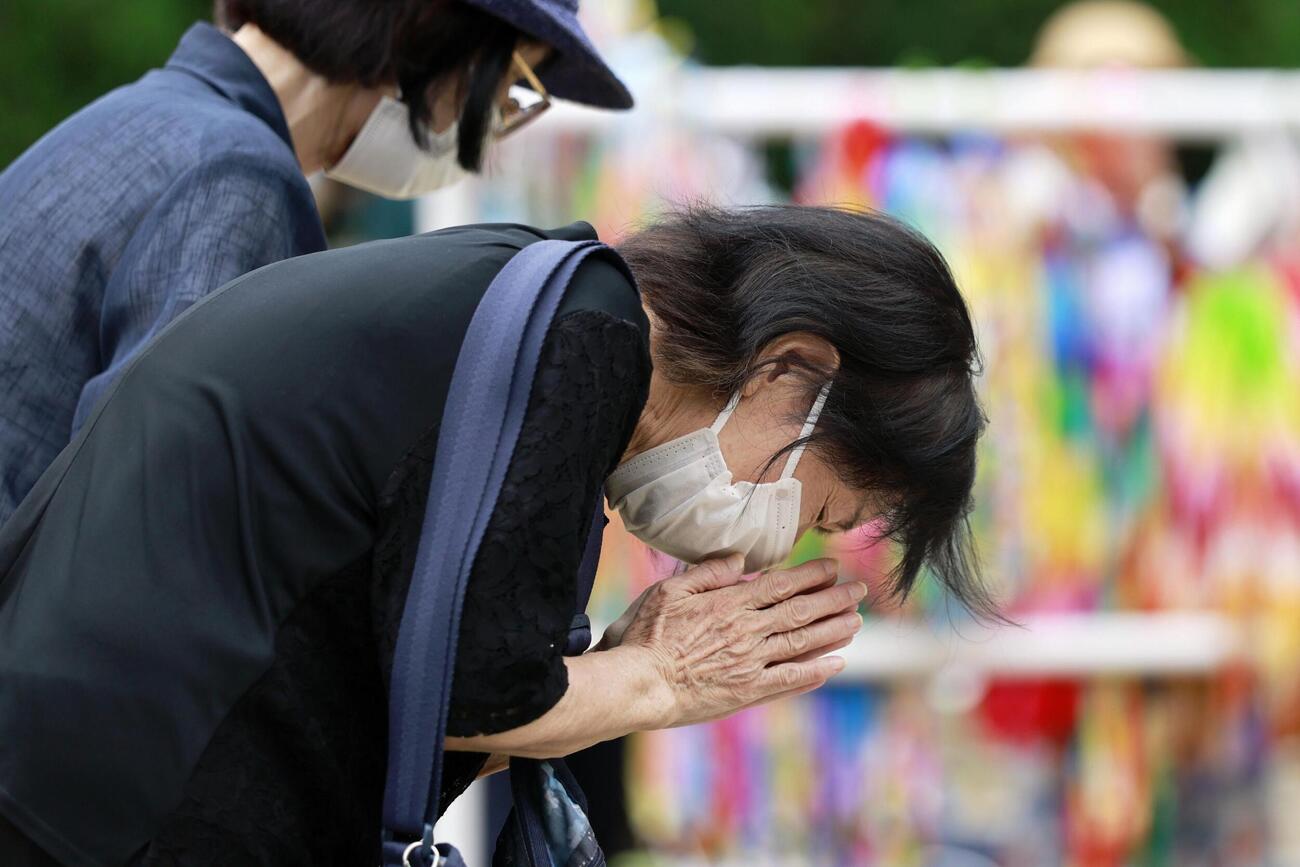 原爆落下中心地碑に手を合わせる女性（共同）