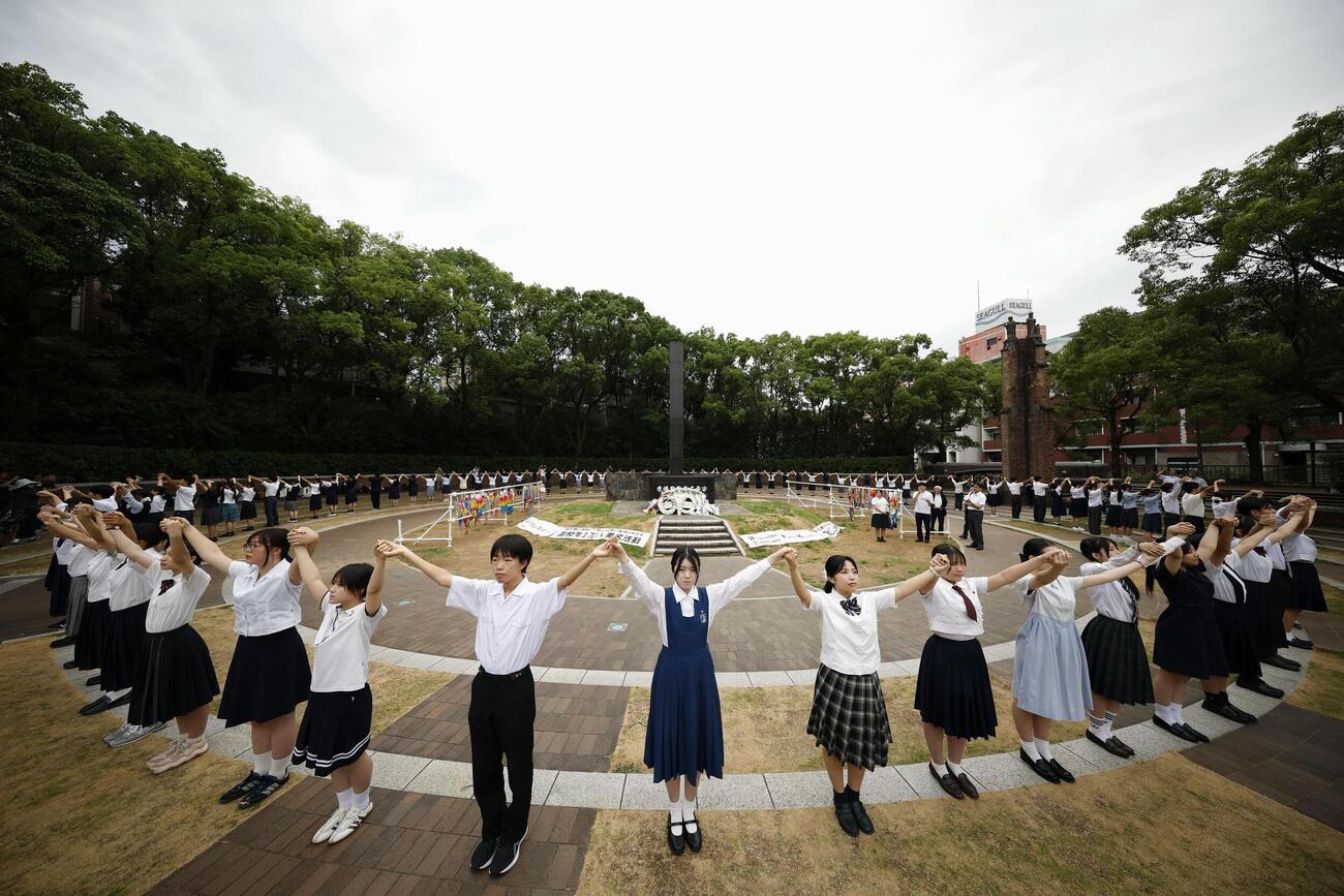 原爆落下中心地碑を囲む「高校生平和大使」らによる「人間の鎖」（共同）