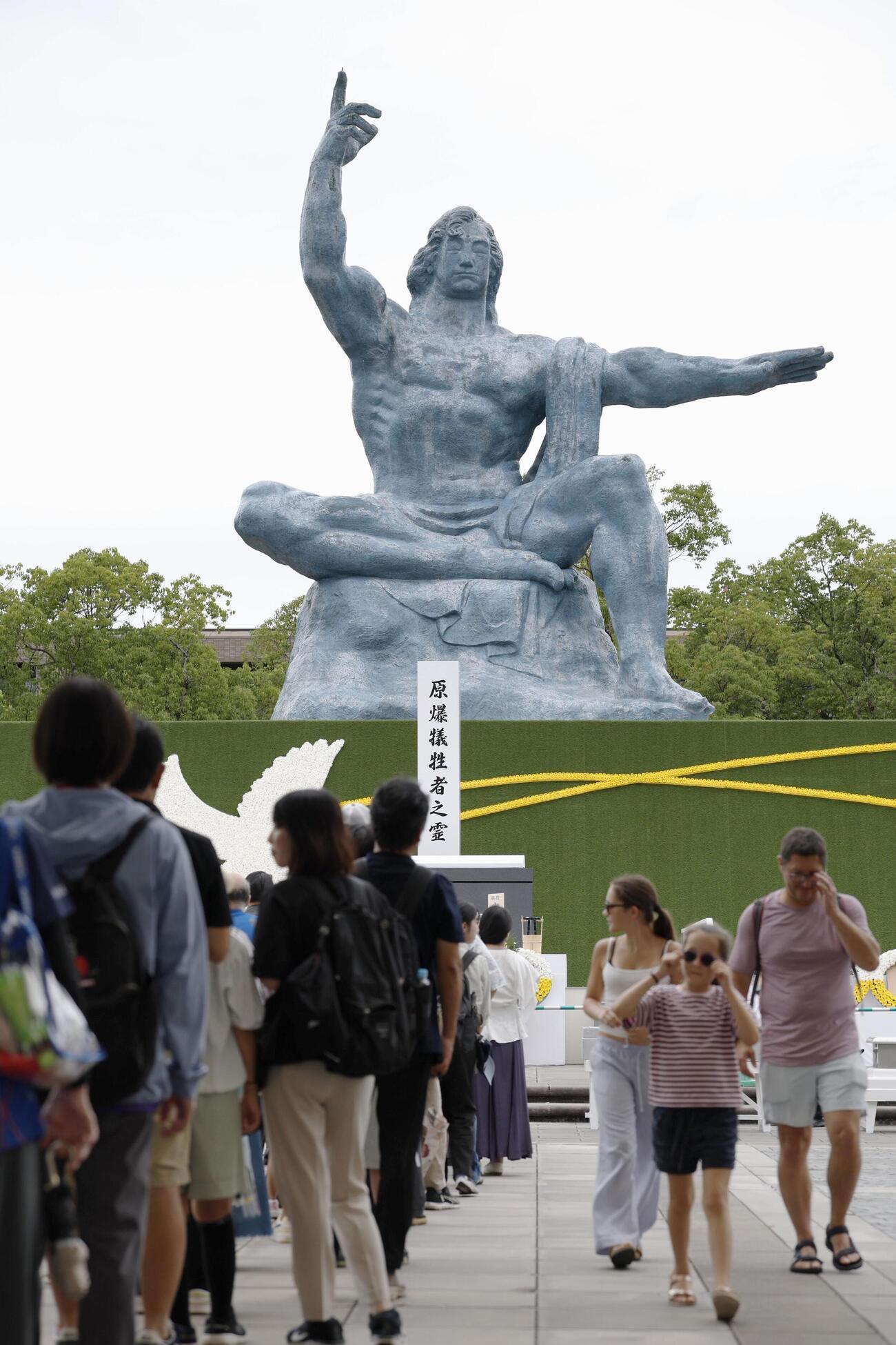 長崎市の平和公園を訪れ、平和祈念像の前に列を作る人たち（共同）