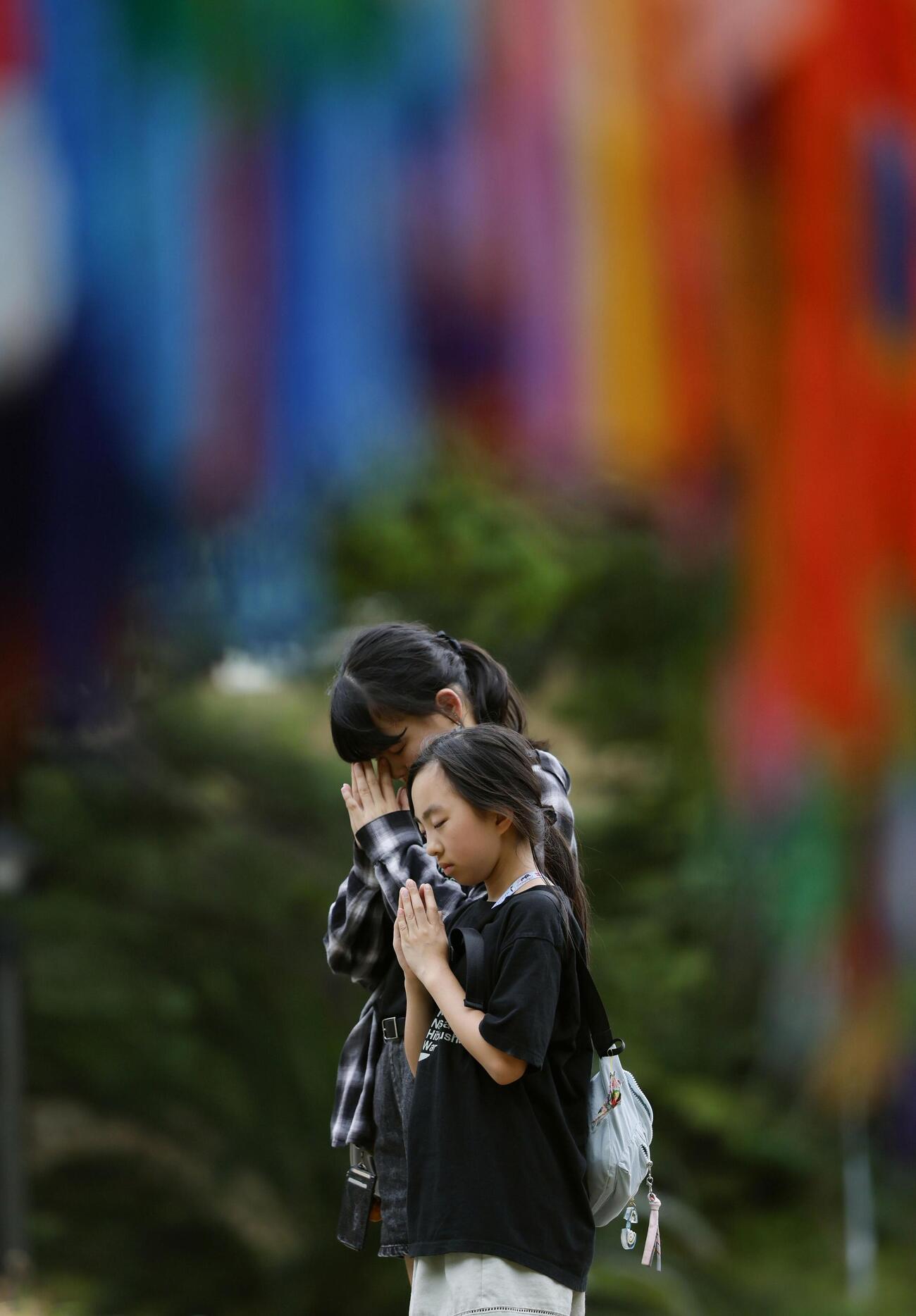長崎市の爆心地公園で手を合わせる女の子ら（共同）