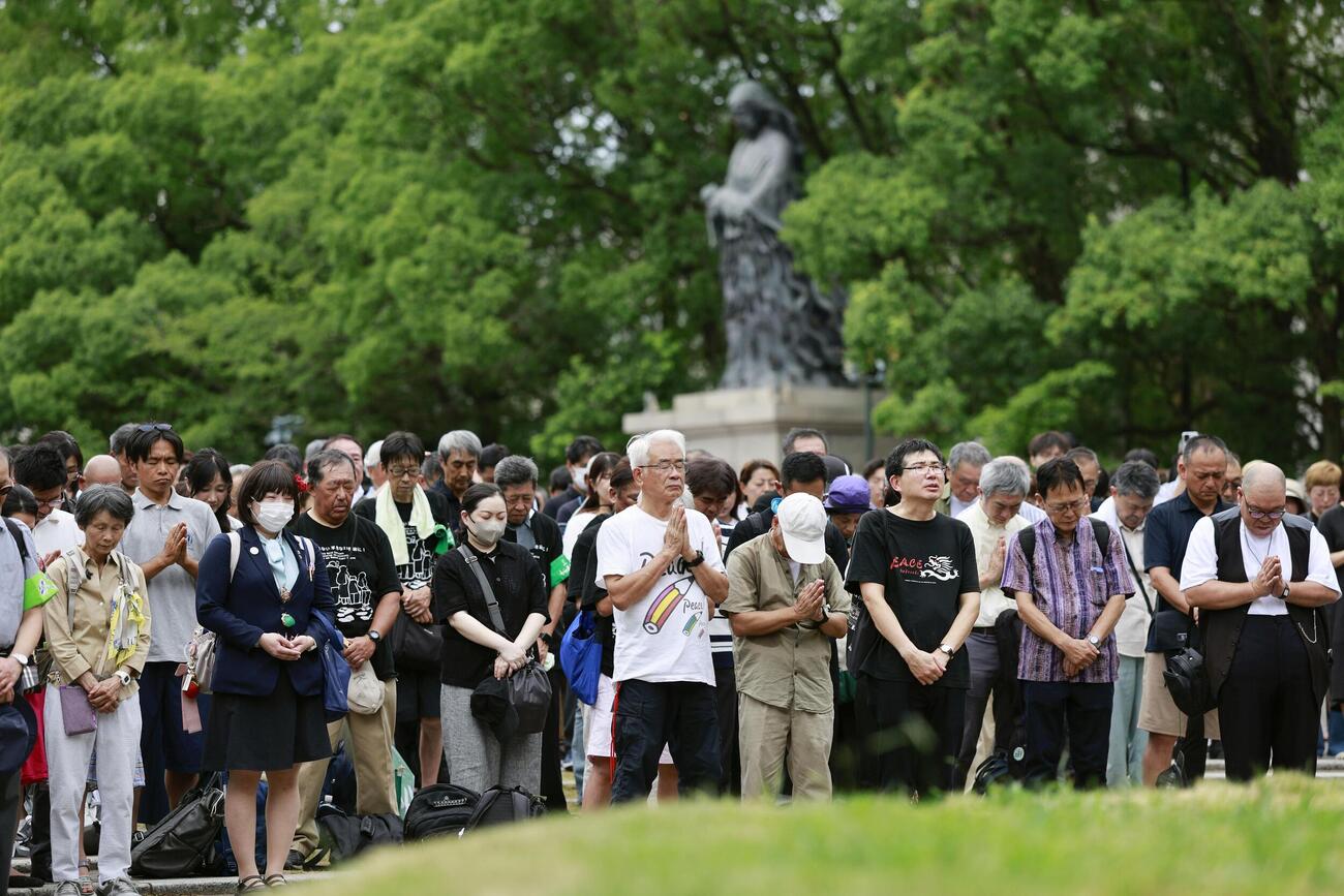 長崎市の爆心地公園で、原爆がさく裂した時刻に合わせ黙とうする人たち（共同）