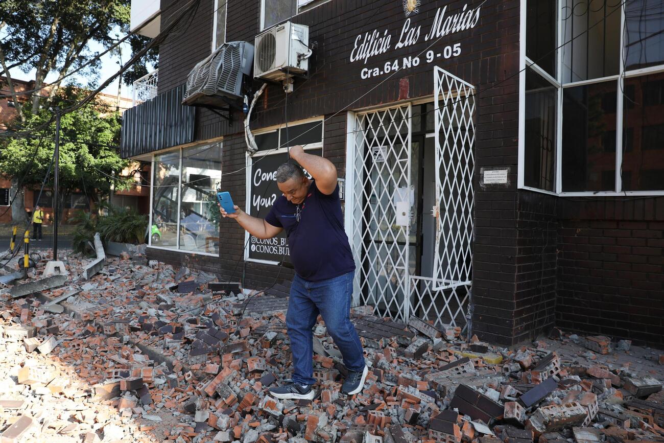 10日、コロンビア西部で発生した地震後、建物から離れる男性（AP＝共同）