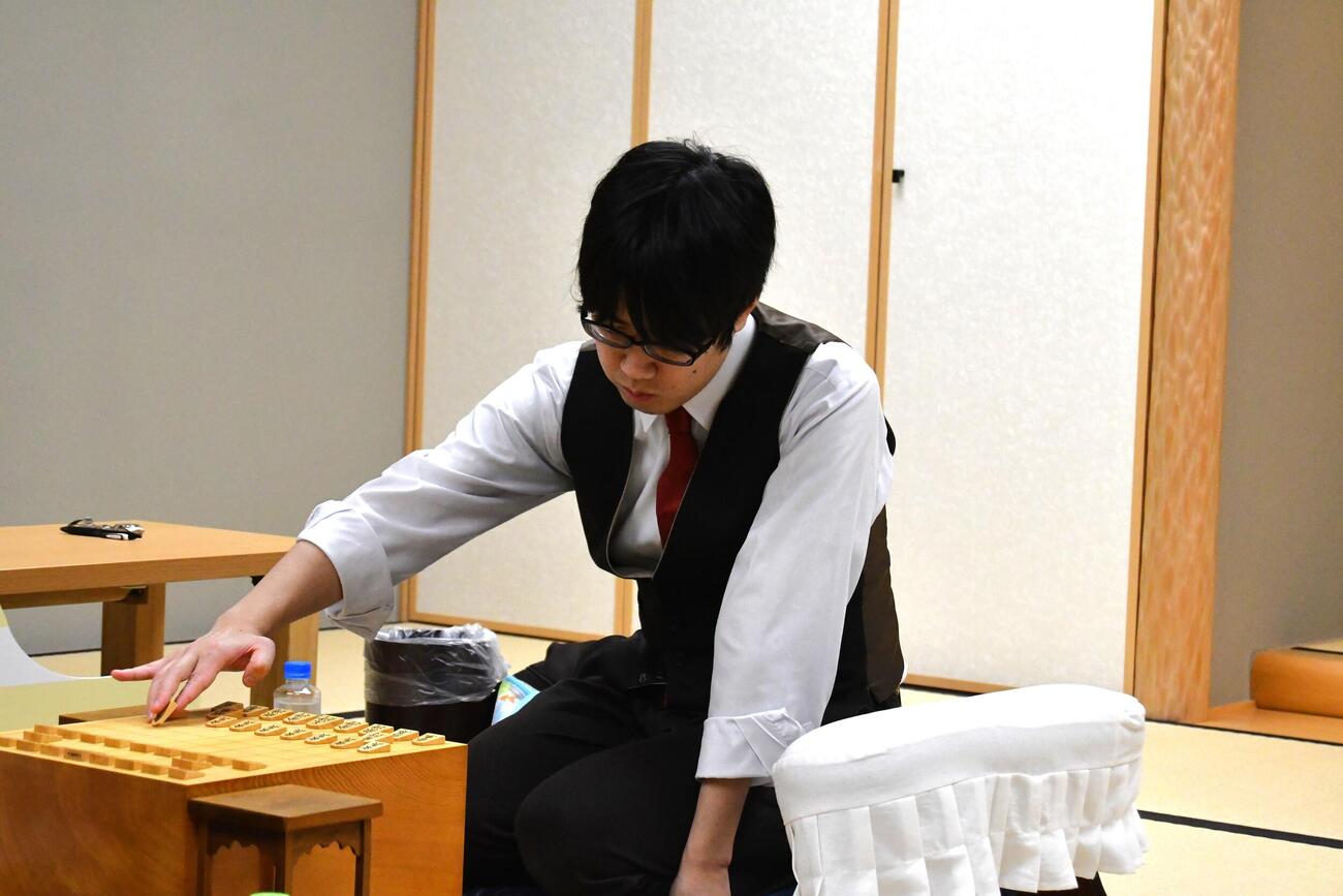 スーツを脱いで早くも闘志満々で初手を指す服部慎一郎七段