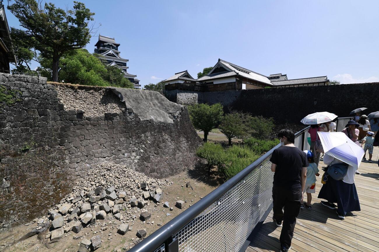 地震発生以来初めて開園した熊本城で、特別見学通路を通り天守閣に向かう来園者。左は7月28日の地震で崩れた石垣（共同）
