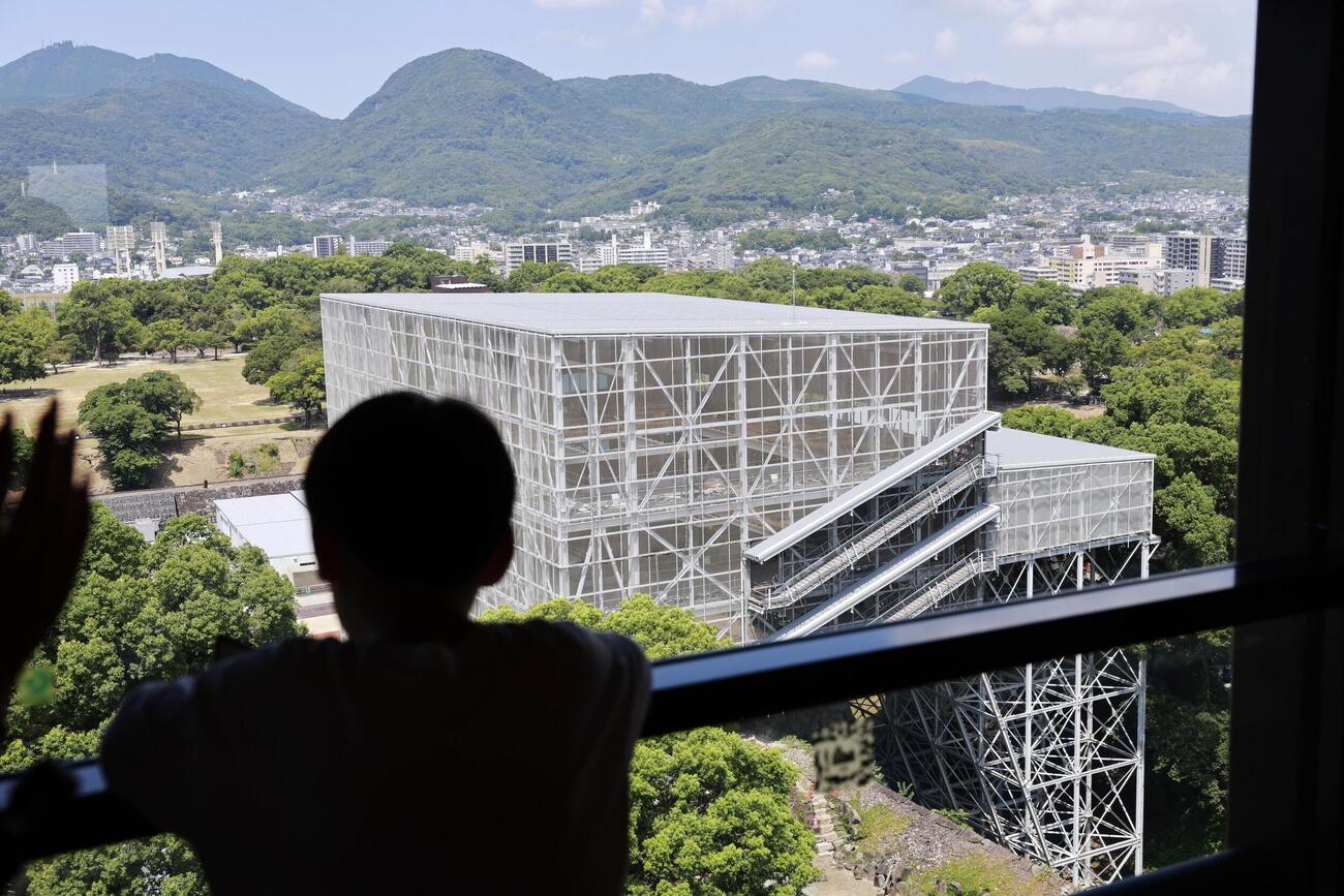 地震発生以来初めて開園した熊本城天守閣から修復中の宇土櫓を望む来園者＝13日午前、熊本市（共同）