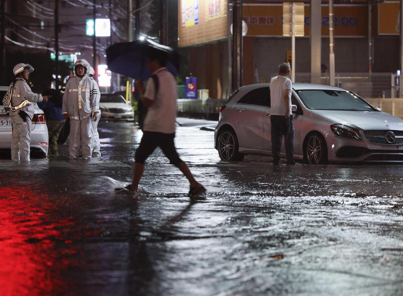 大雨の影響で冠水した千葉県市川市内の道路。車が動かなくなっていた＝13日午後9時57分（共同）