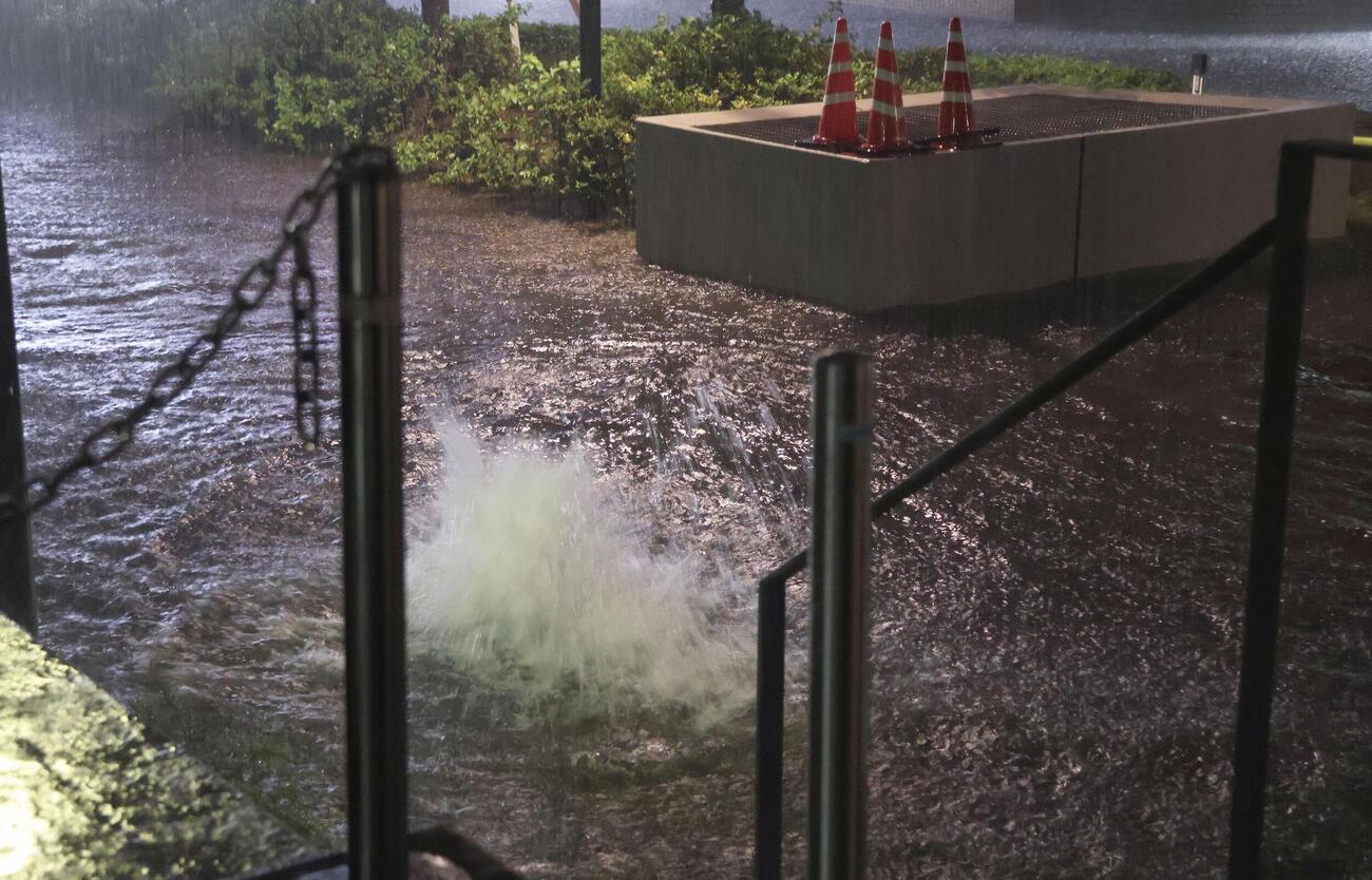大雨の影響で水が噴き出すマンホール＝13日午後7時2分、千葉市中央区（共同）