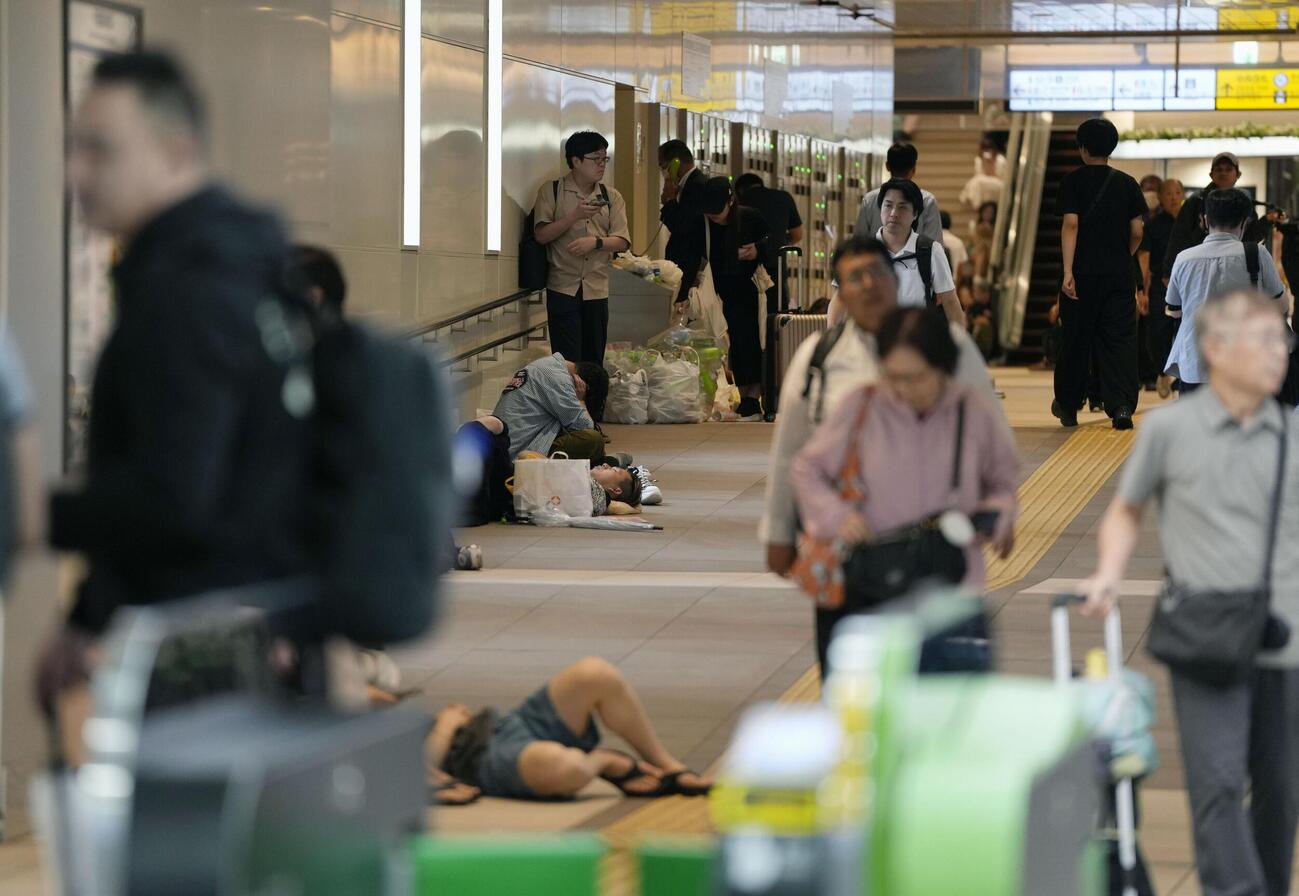 大雨の影響で運休が続いたJR千葉駅で、座り込んだり寝転んだりする人たち＝14日午前7時23分