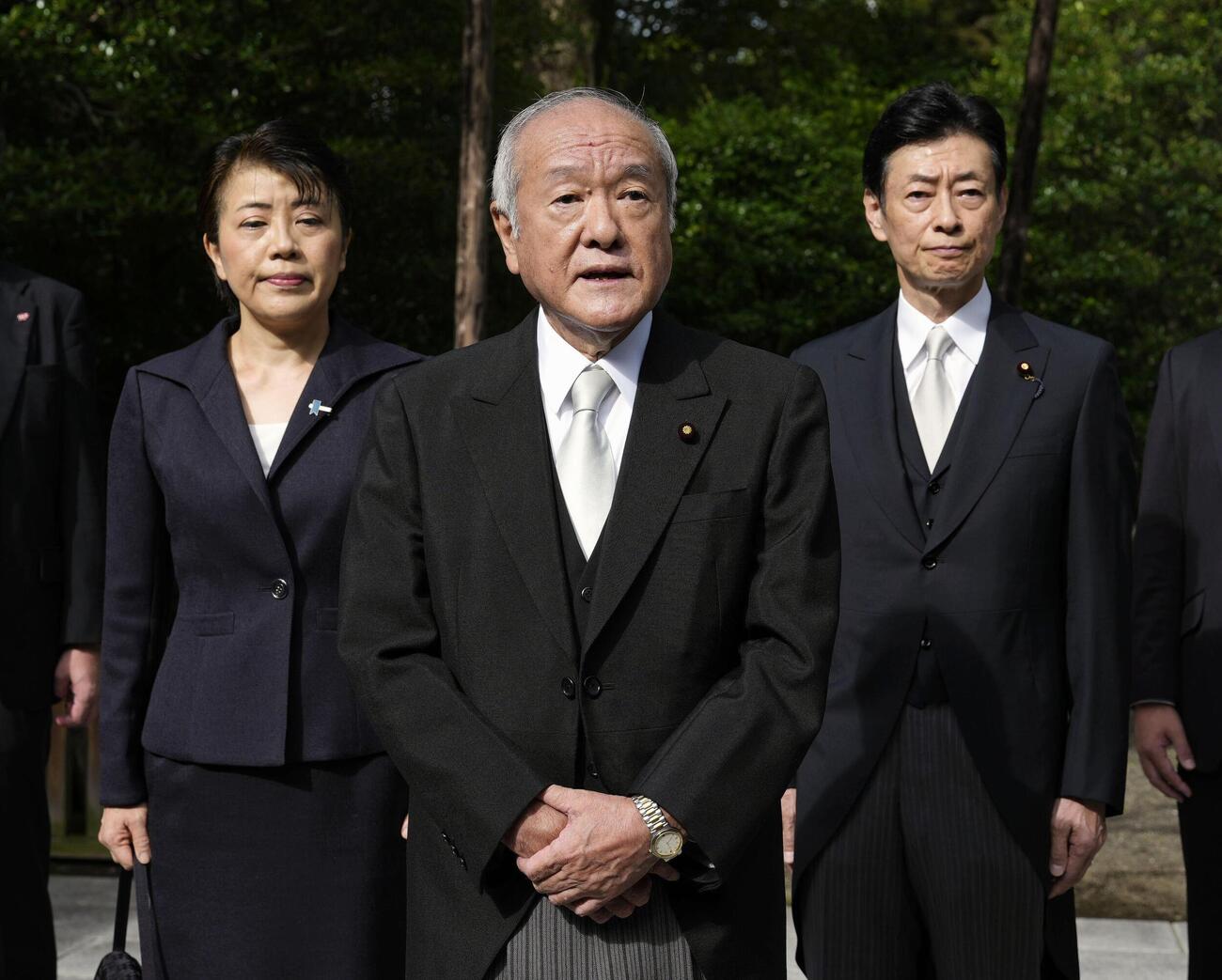 靖国神社を参拝後、記者団の取材に応じる自民党の鈴木幹事長。左は有村総務会長、右は西村選対委員長（共同）