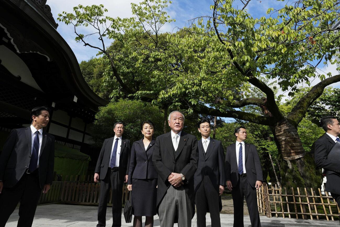 靖国神社を参拝後、取材に応じる自民党の鈴木幹事長（中央）。同左は有村総務会長、同右は西村選対委員長（共同）