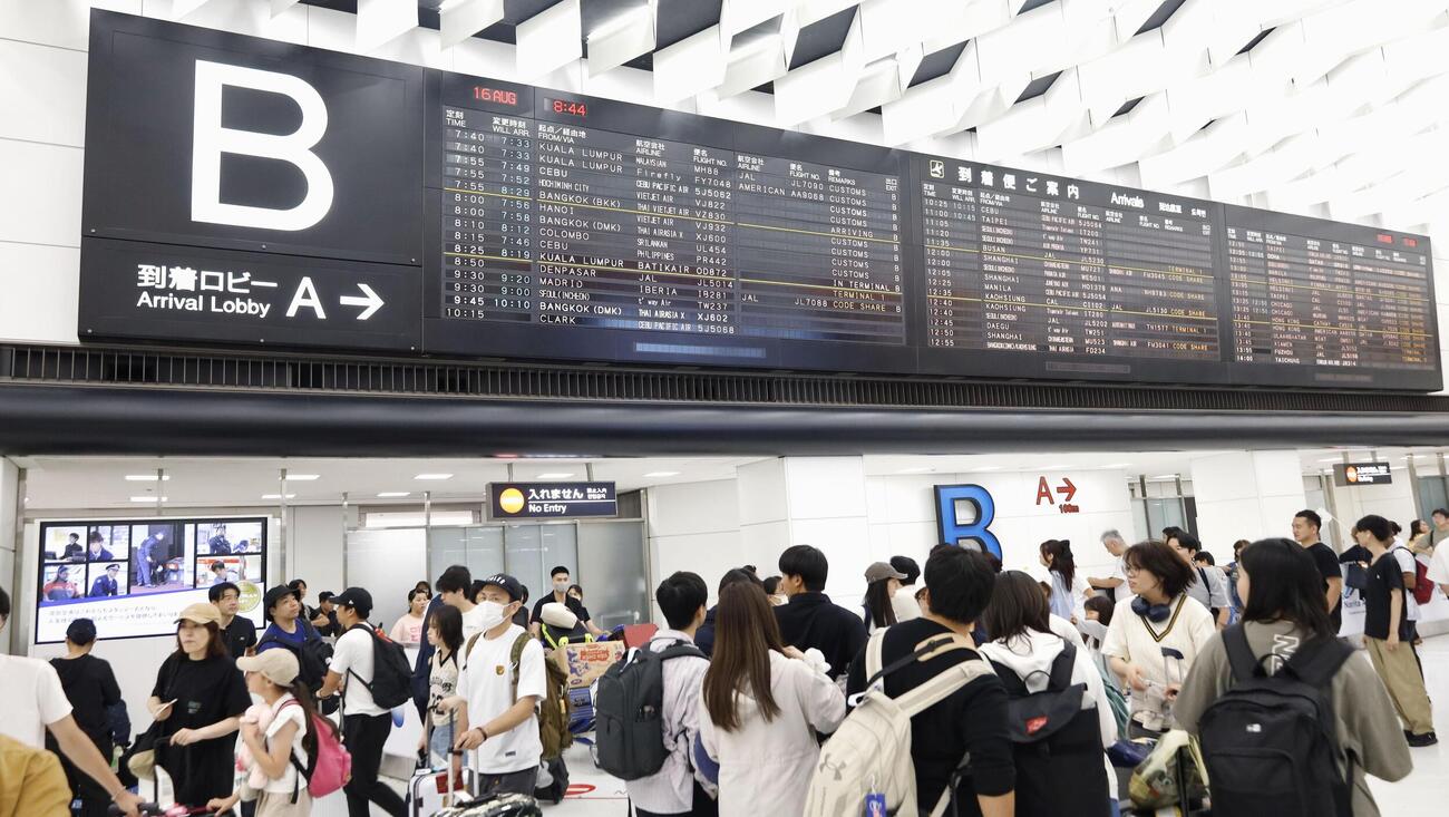帰国した旅行客らが行き交う成田空港の到着ロビー（共同）