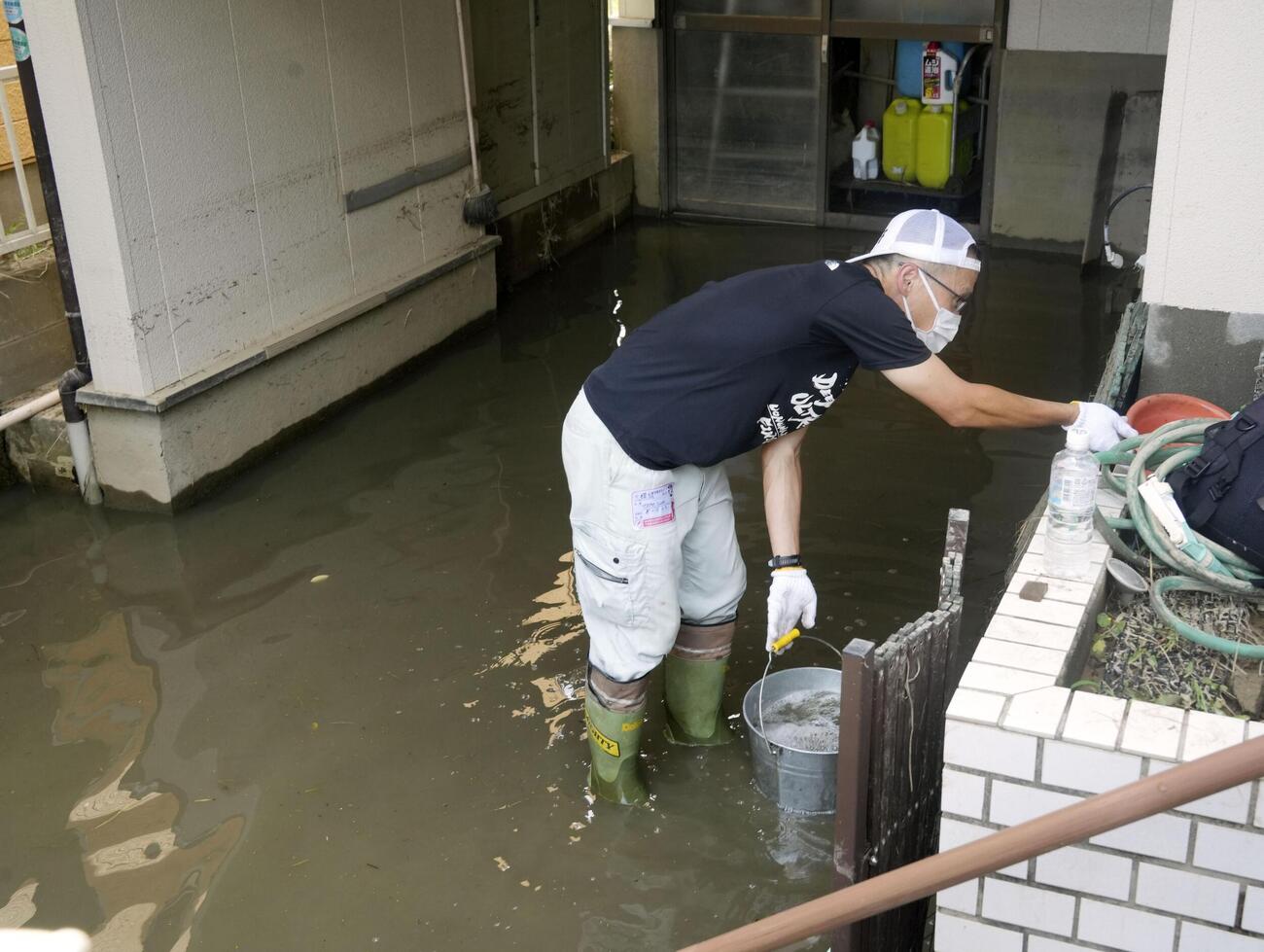 浸水した駐車場で作業をする人（共同）