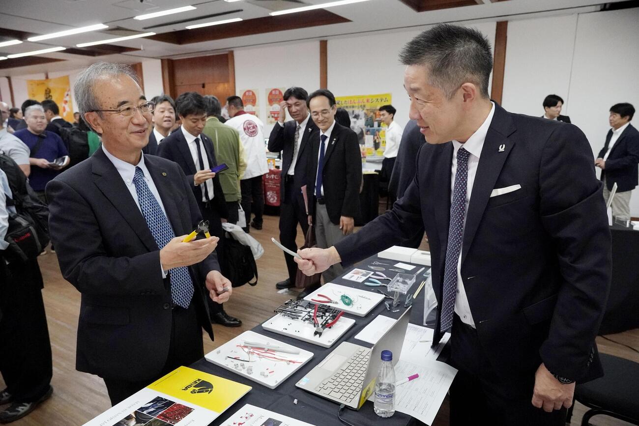 新潟県でつくられる工具や刃物を紹介するコーナーを訪れた花角英世知事（左）（共同）