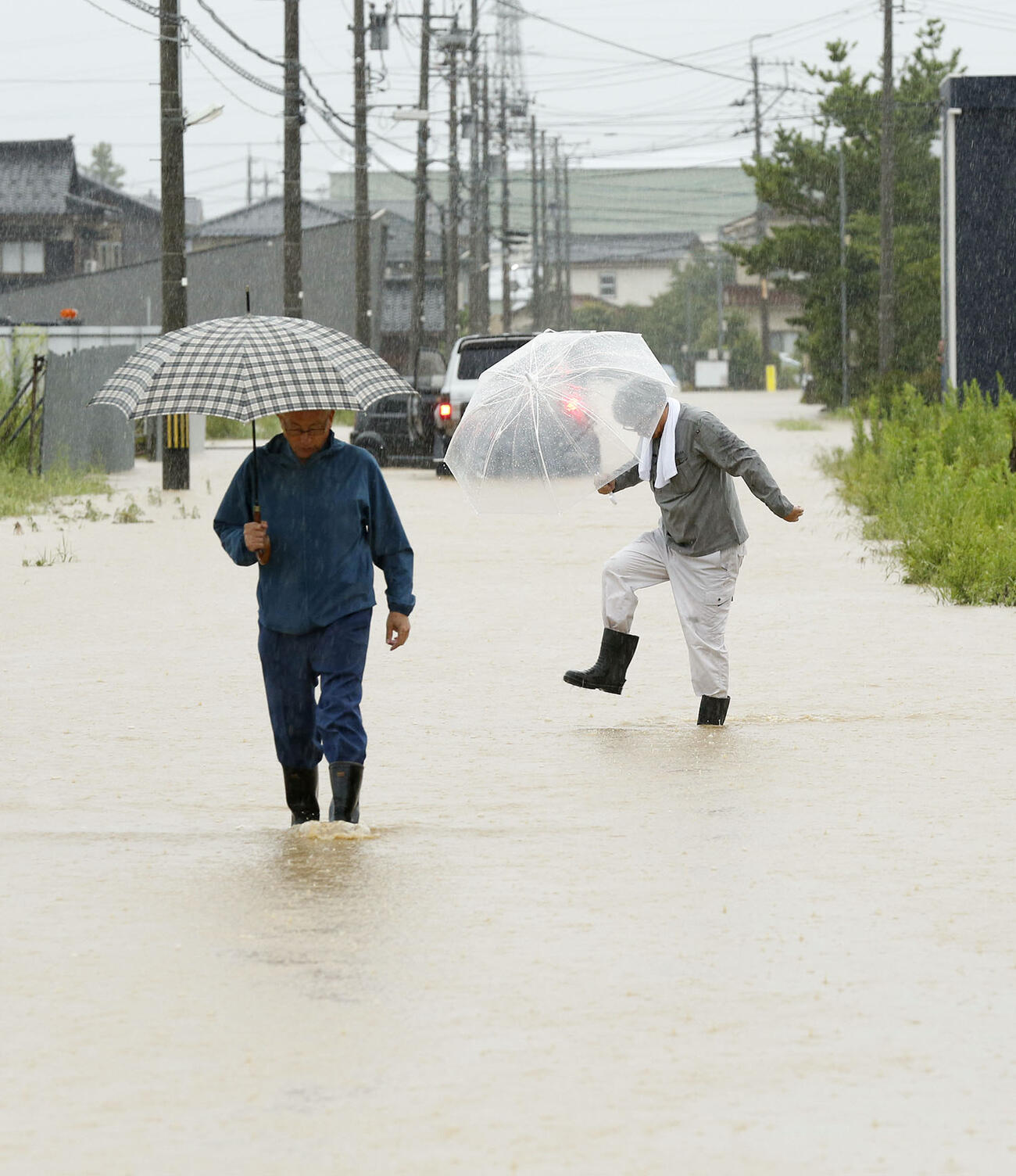 大雨で冠水した石川県羽咋市で道路を歩く人たち（共同）