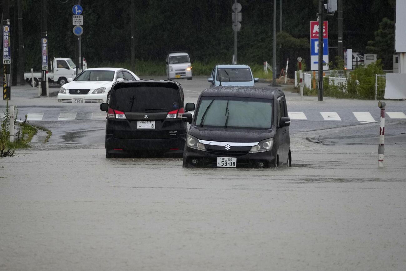 大雨の影響で冠水した富山県氷見市の道路に残された車両（共同）