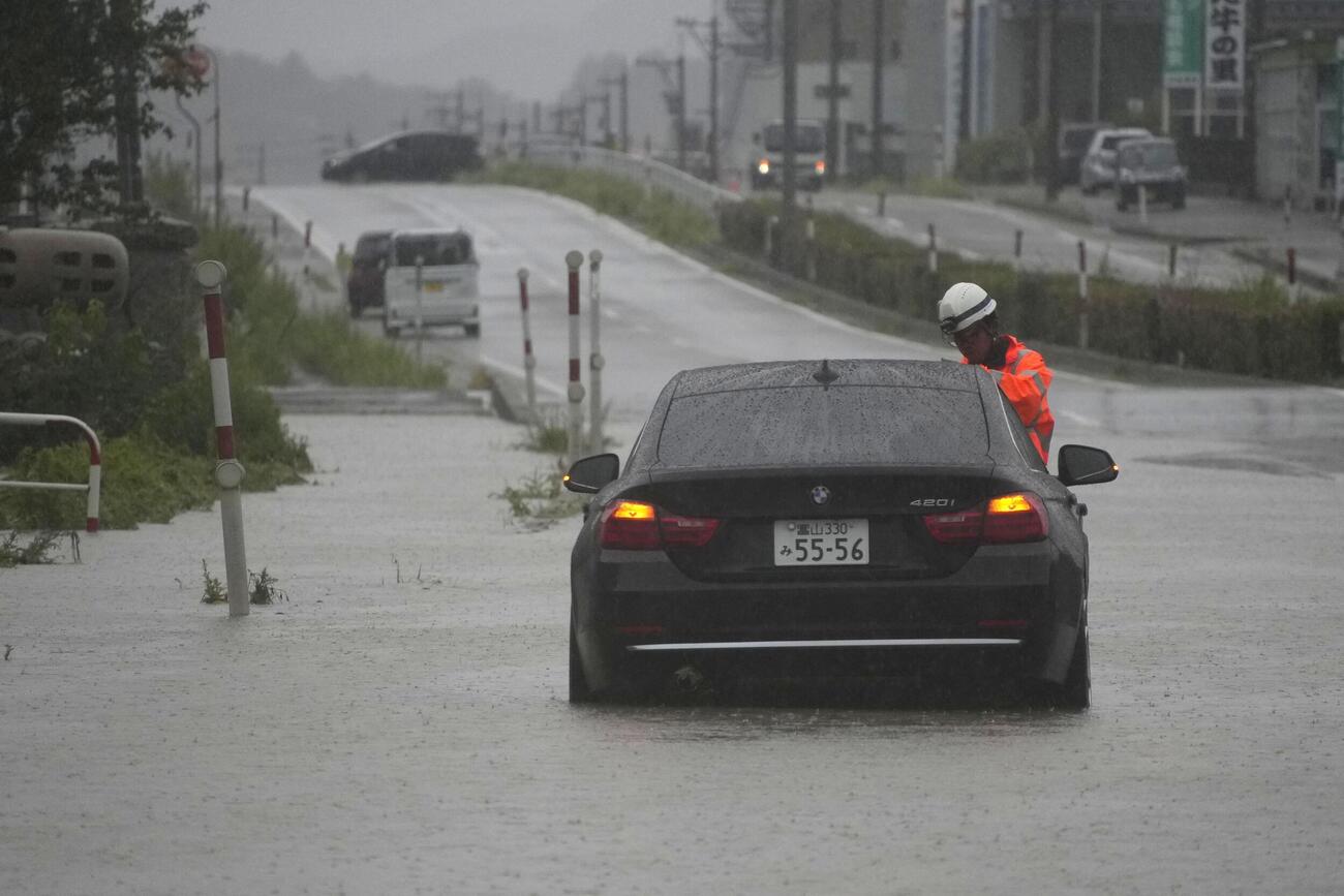 大雨の影響で冠水した富山県氷見市の道路に残された車両（共同）