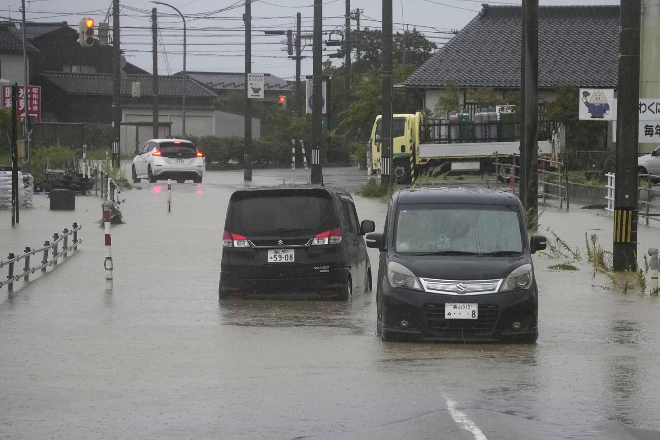 大雨の影響で冠水した道路に残された車両（共同）