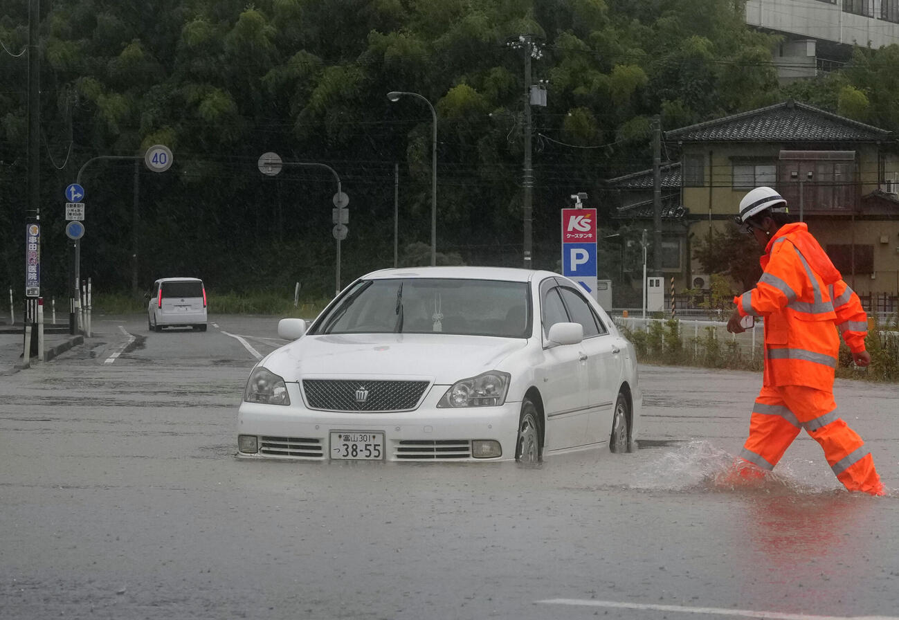 大雨の影響で冠水した富山県氷見市の道路に残された車両（共同）