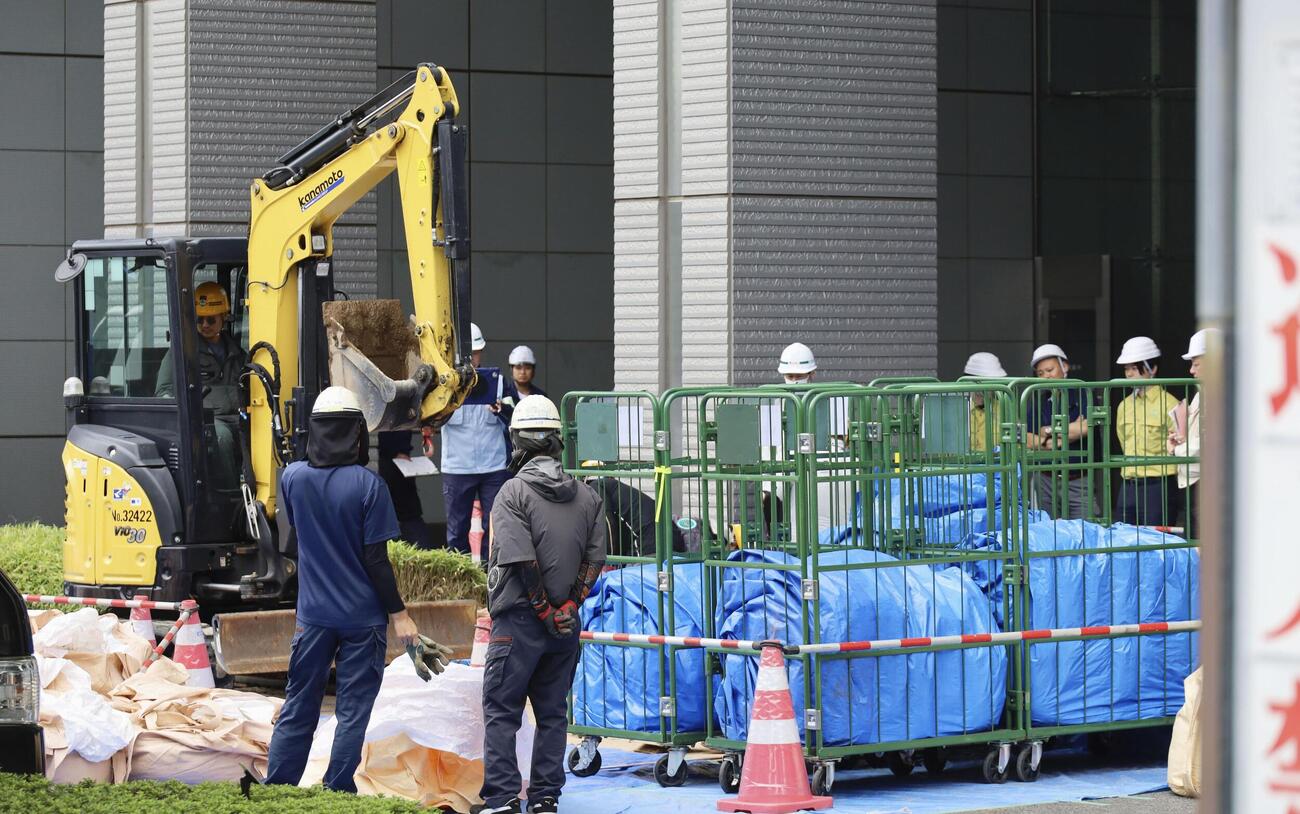 さいたま新都心合同庁舎1号館で、花壇に除染土を運ぶ作業員ら＝30日午前、さいたま市(共同)