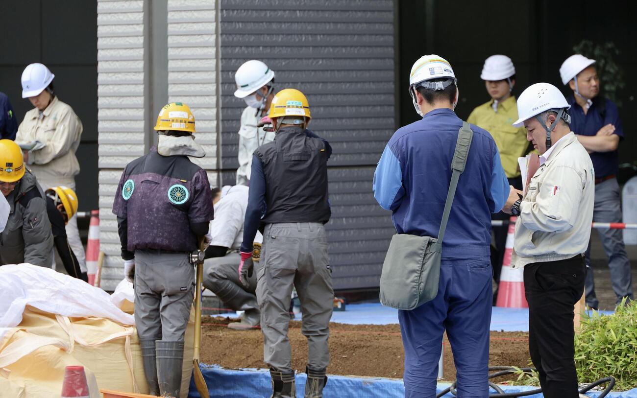 さいたま新都心合同庁舎1号館で、花壇へ除染土を運ぶ作業員ら＝30日午前、さいたま市(共同)