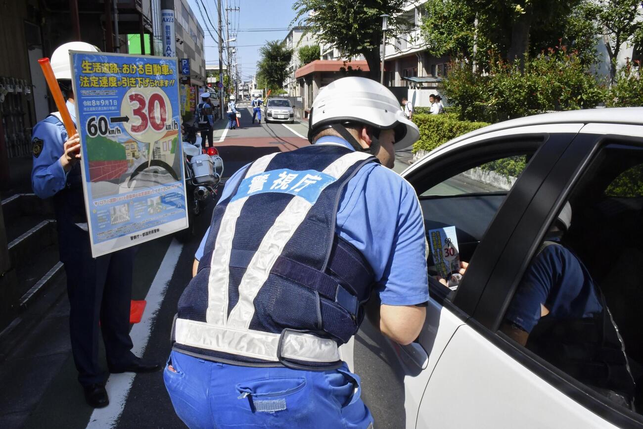 ドライバーに生活道路の法定速度引き下げを周知する警視庁の警察官（共同）