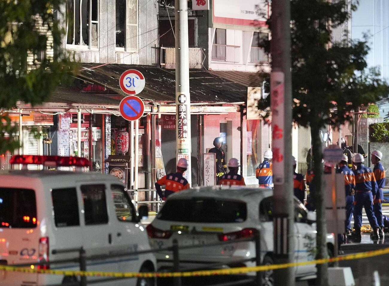 火災があった明倫商店街の入り口に集まる消防団員＝31日午後7時44分、三重県伊勢市
