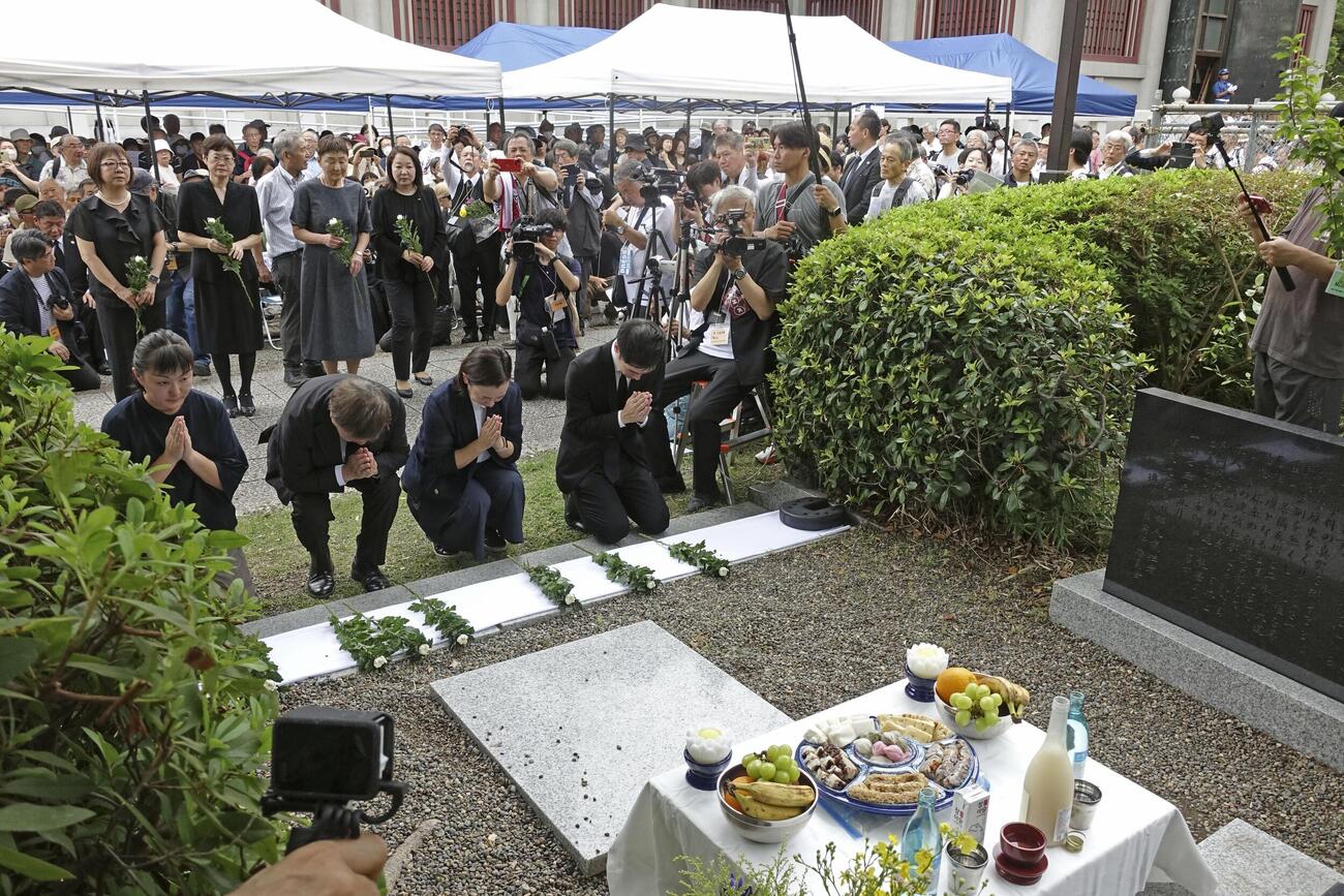 虐殺された朝鮮人の追悼碑に献花し、祈る参列者たち（共同）