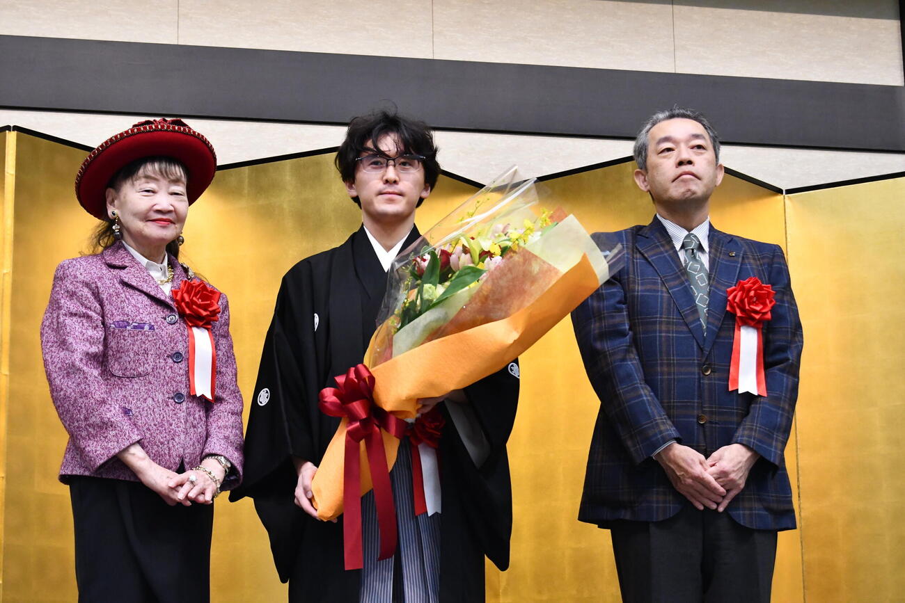 アパホテルの元谷芙美子社長（左）とアパグループの元谷一志社長（右）とともに花束を手にする伊藤匠叡王