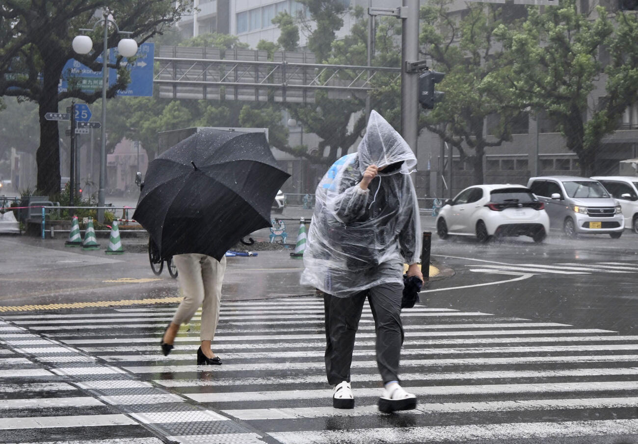 激しい雨に見舞われた宮崎市内を歩く人たち＝4日午後（共同）