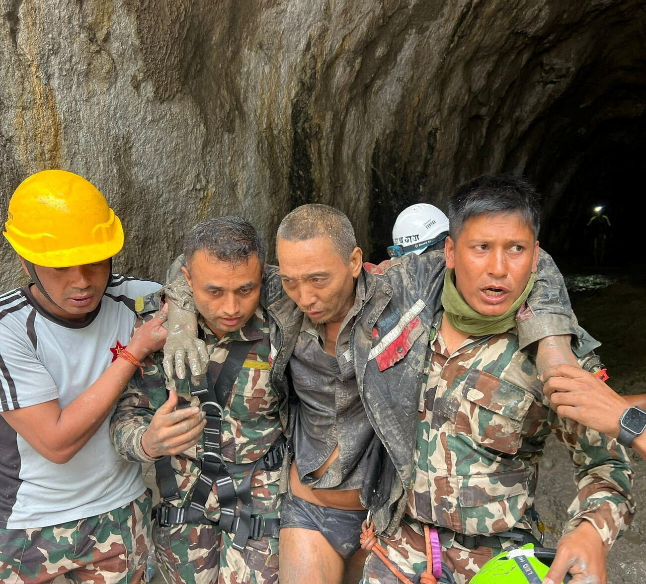 土石流で被災した水力発電所のトンネルから救助され、担がれる中国人＝5日、ネパール中部ラスワ郡（ネパール軍提供・ロイター＝共同）