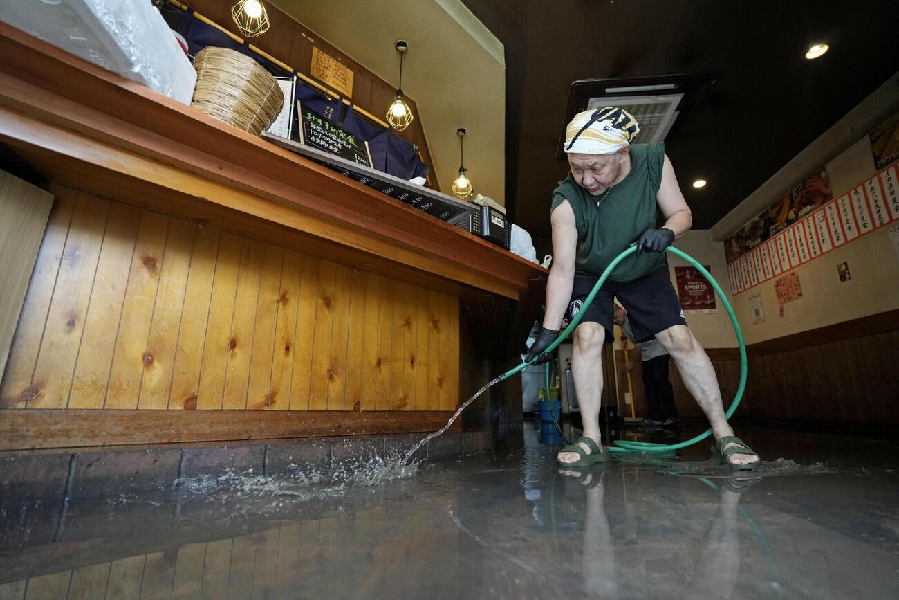大雨の影響で居酒屋の店舗内に入り込んだ泥を掃除する人＝9日午前10時9分、名古屋市名東区（共同）