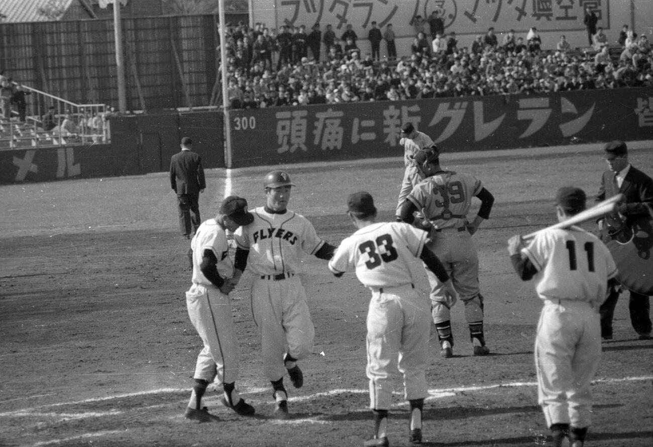 1959年4月、東映対阪急　3回裏東映2死三塁、6番張本勲左翼手は石井茂雄投手から右翼へプロ初本塁打を放ち、山本八郎（左）、毒島章一（背番号33）、稲垣正夫（背番号11）らに迎えられる。捕手は富山大