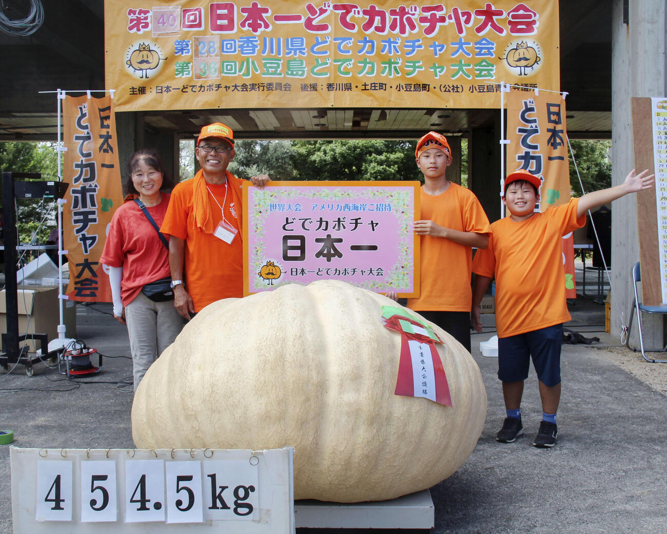 「日本一どでカボチャ大会」で優勝し、笑顔の田辺憲明さん（左から2人目）と3位に入った孫の響人さん（同3人目）（共同）