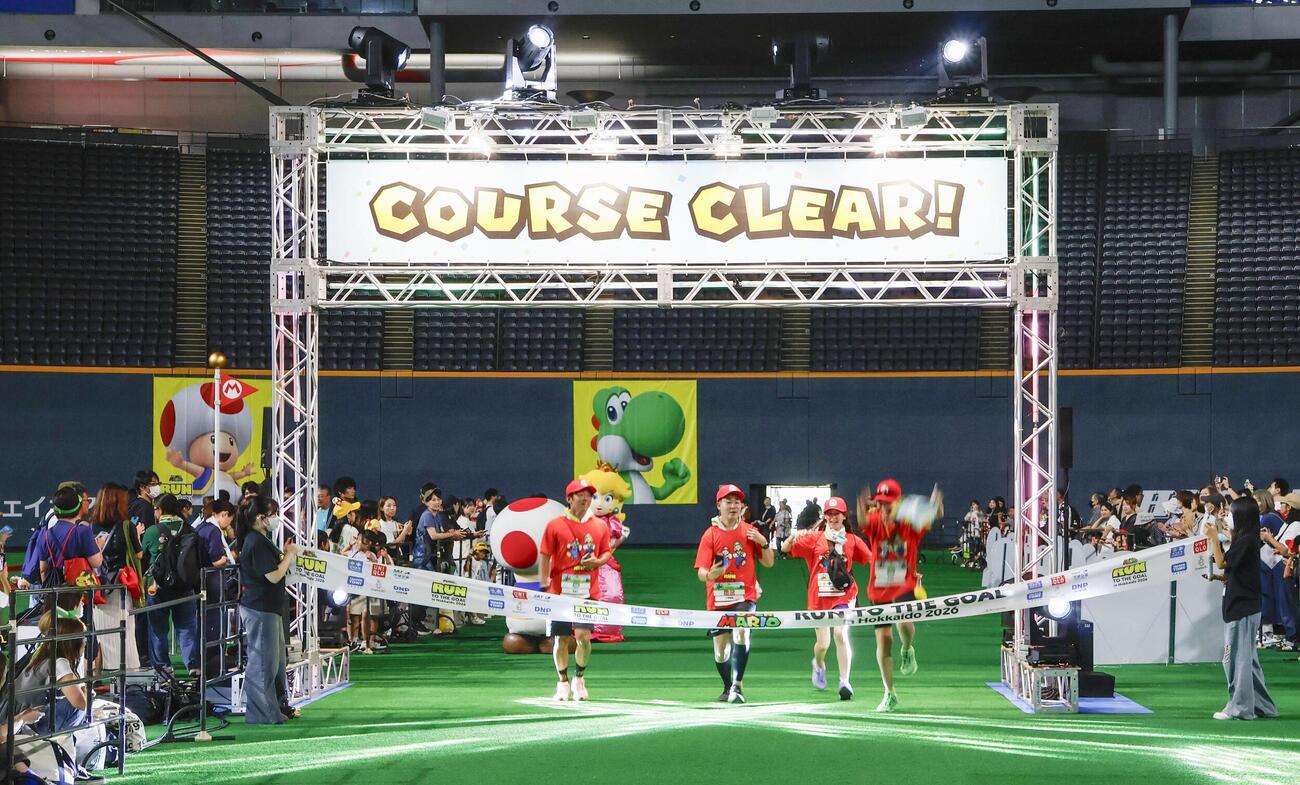 「スーパーマリオ」の世界を表現したコースを走り、ゴールテープを切る参加者＝13日午前、札幌市（共同）