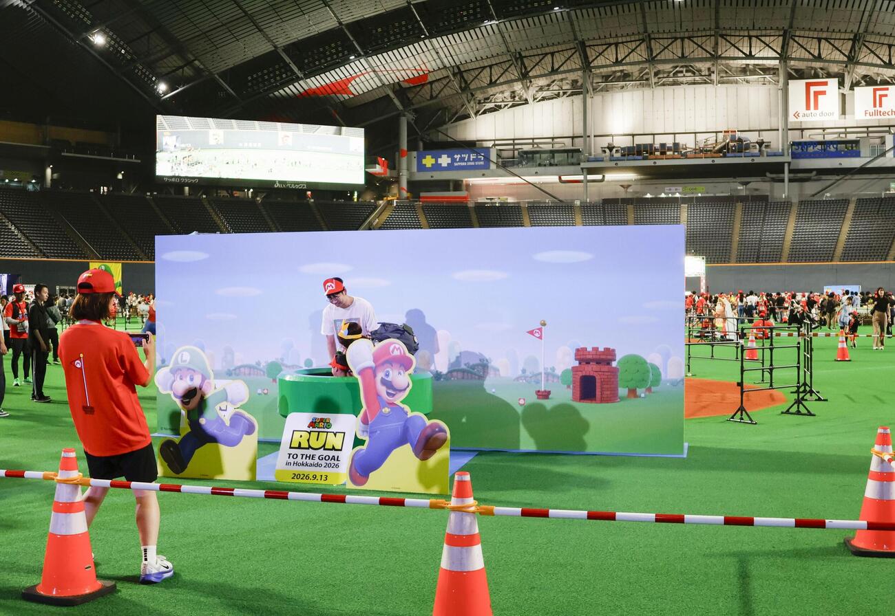 マリオの世界を再現したフォトスポットで記念撮影する参加者＝13日午前、札幌市(共同)