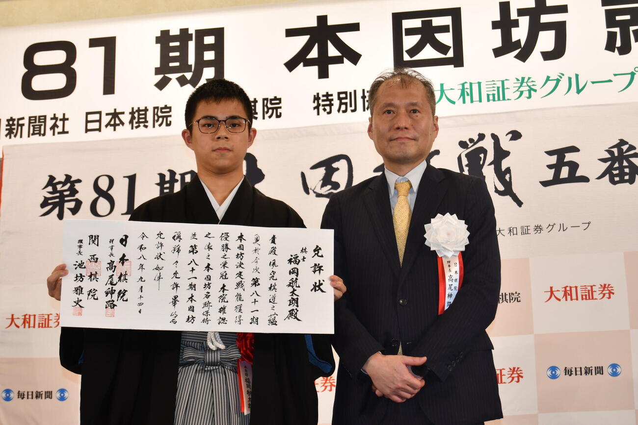 福岡航太朗本因坊（左）は日本棋院の高尾紳路理事長から渡された允許（いんきょ）状を手にする