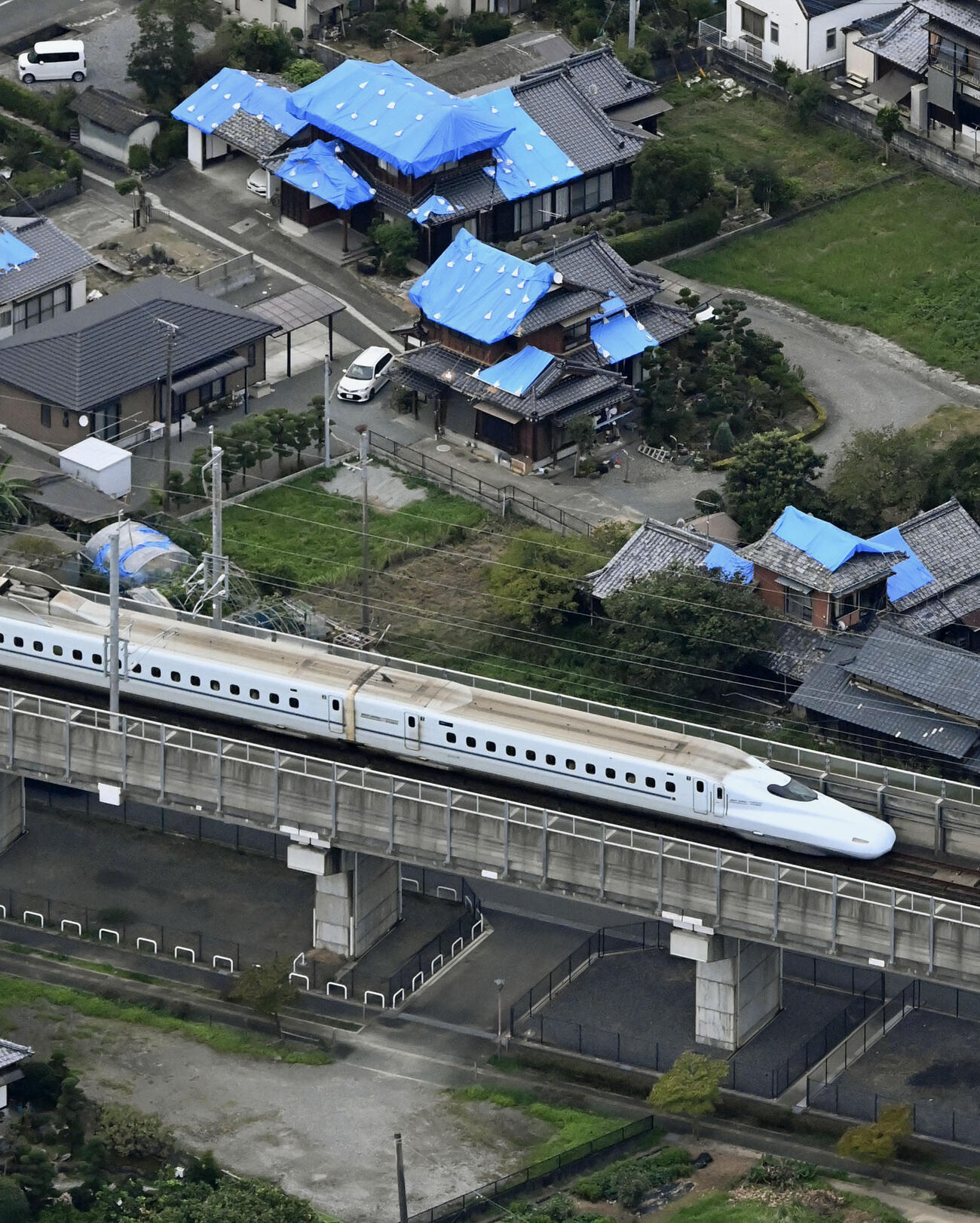 熊本地震で被災した家屋の横を走行する九州新幹線。52日ぶりに全線で運転を再開した（共同）