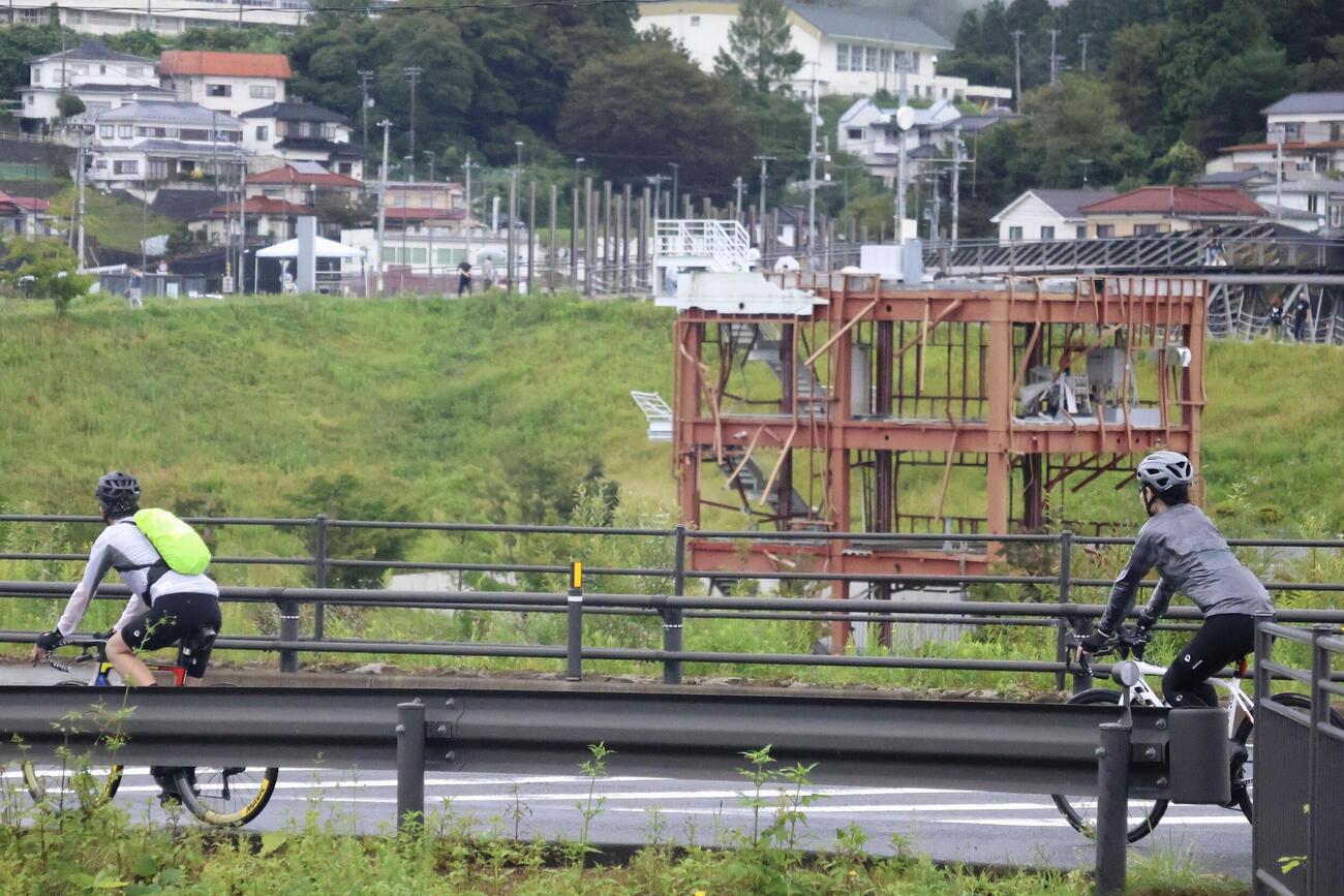 「ツール・ド・東北2026」で宮城県南三陸町の旧防災対策庁舎前を走る参加者（共同）