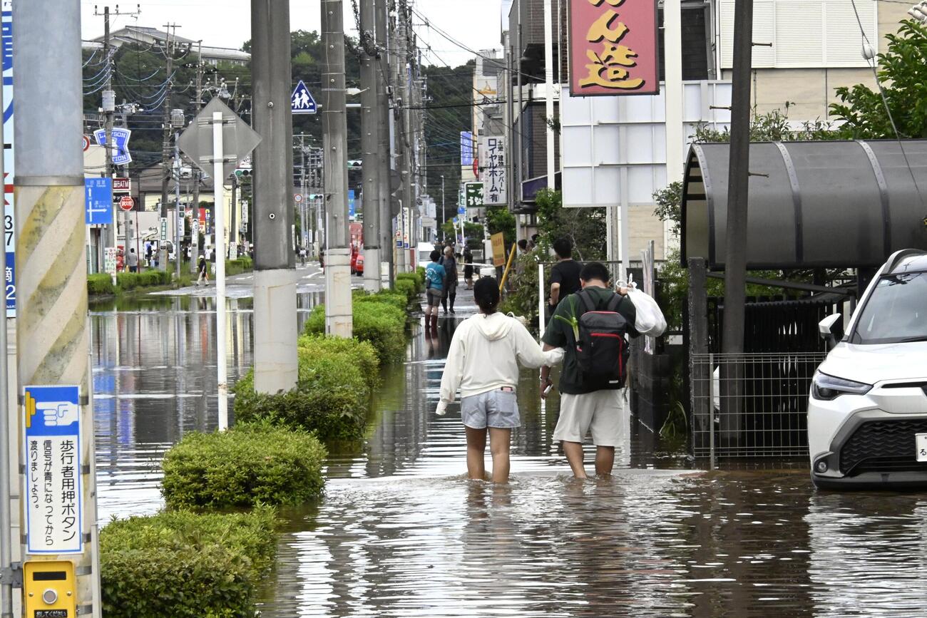 千葉県佐倉市の高崎川が氾濫し、冠水した道路を歩く人たち（共同）