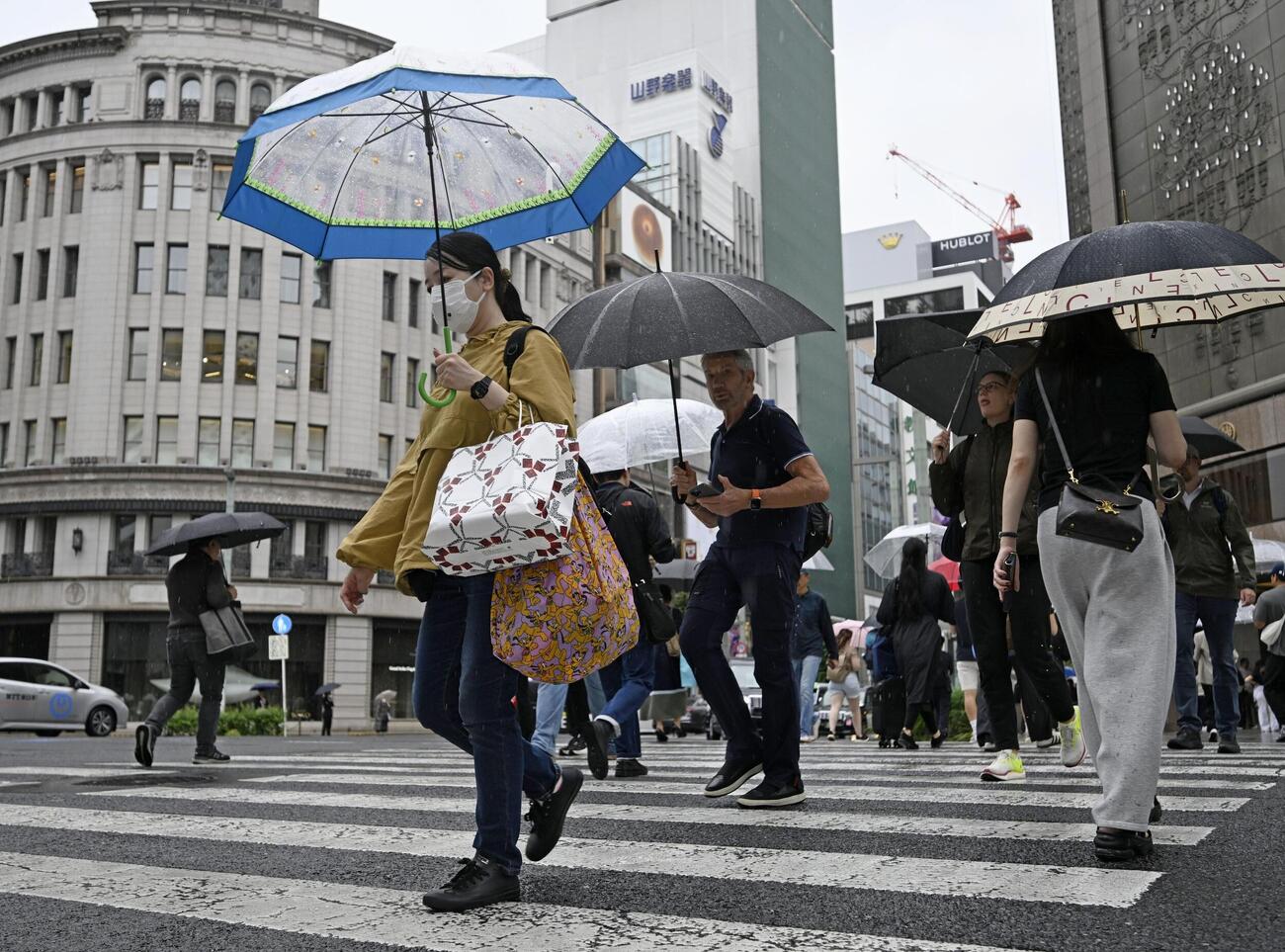 東京・銀座を傘を差して歩く人たち。都心で連続降雨過去最長を記録した（共同）