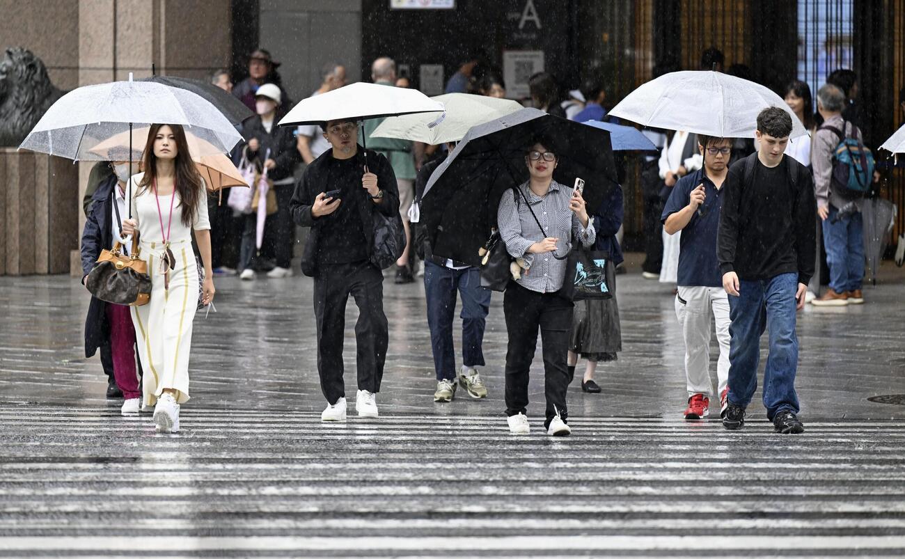 東京・銀座を傘を差して歩く人たち。都心で連続降雨過去最長を記録した（共同）